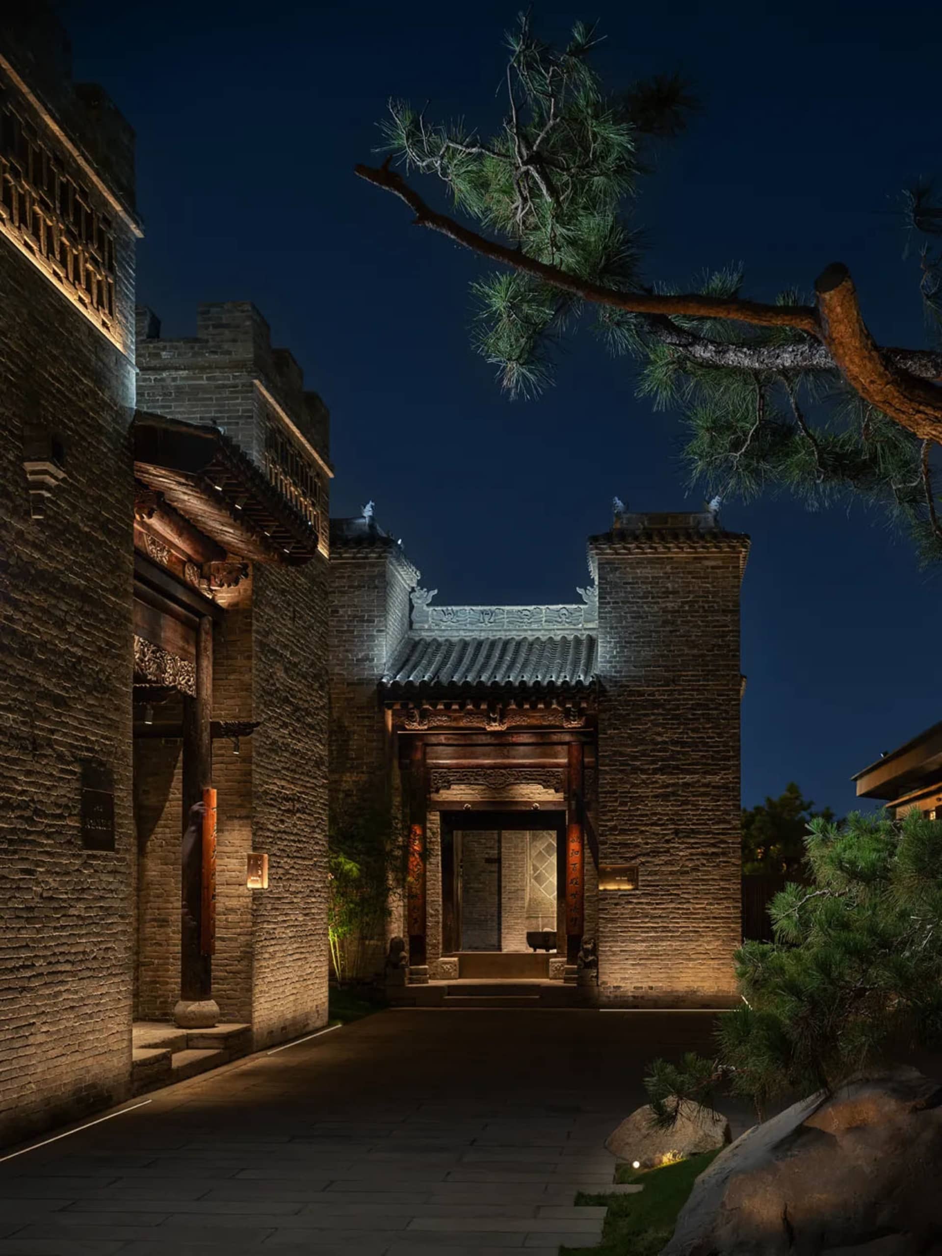 A stone building with an arched doorway and stone roof, set against a dimly lit background