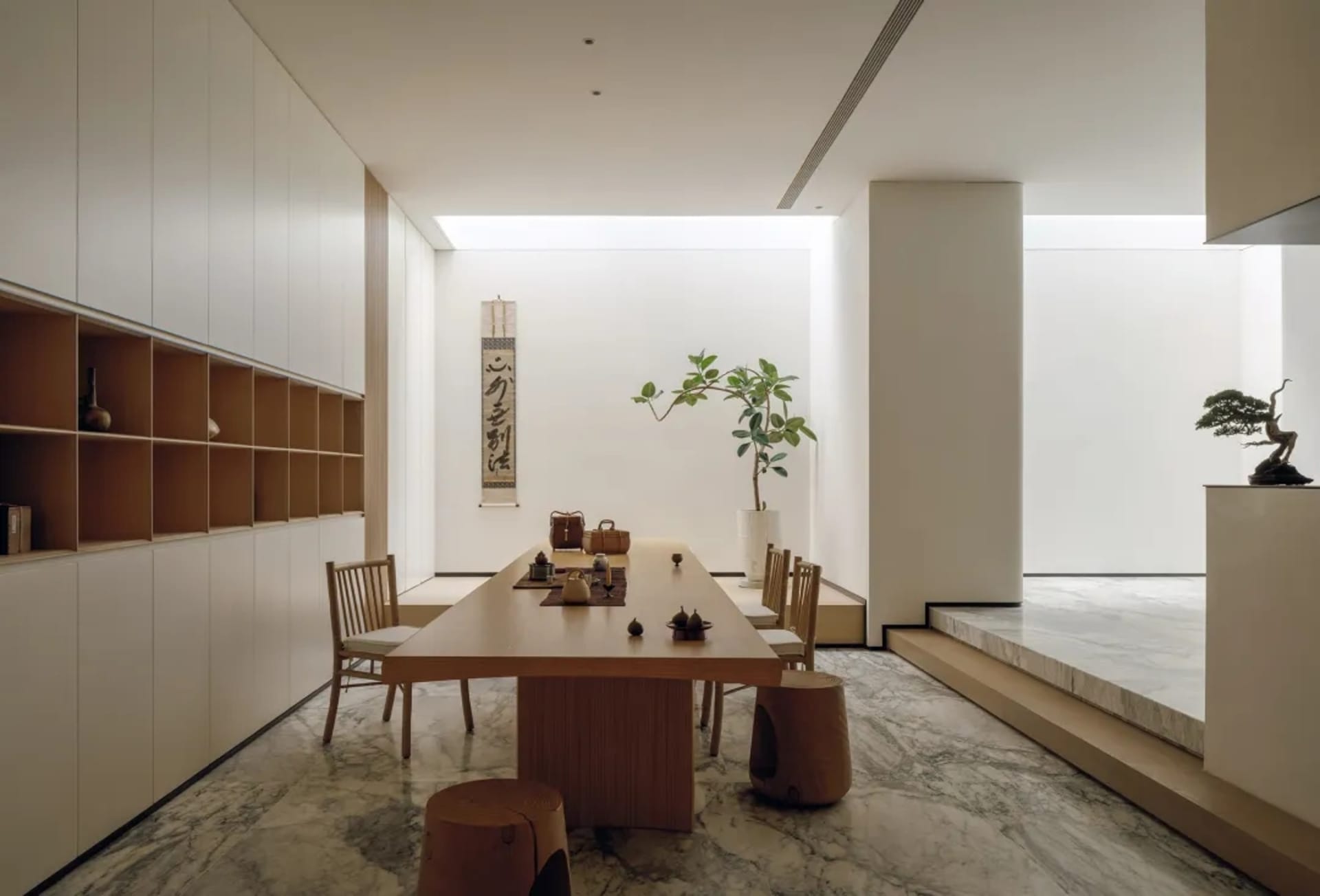 A well-lit dining room with a wooden table and chairs, surrounded by a potted plant, creating a warm and inviting atmosphere