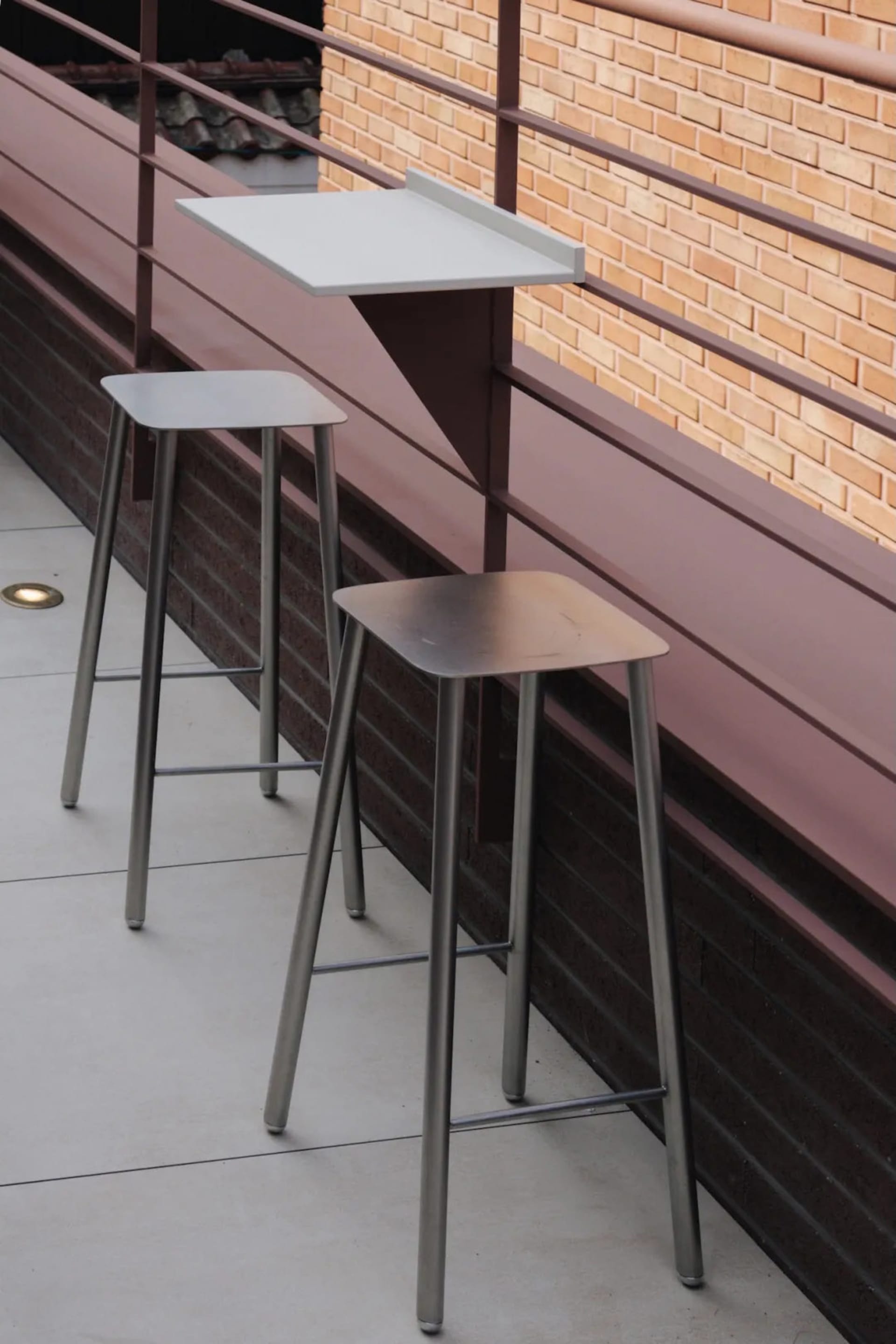 白色鐵製計費桌,鐵製 stools,磚牆,天然光源照亮餐廳空間