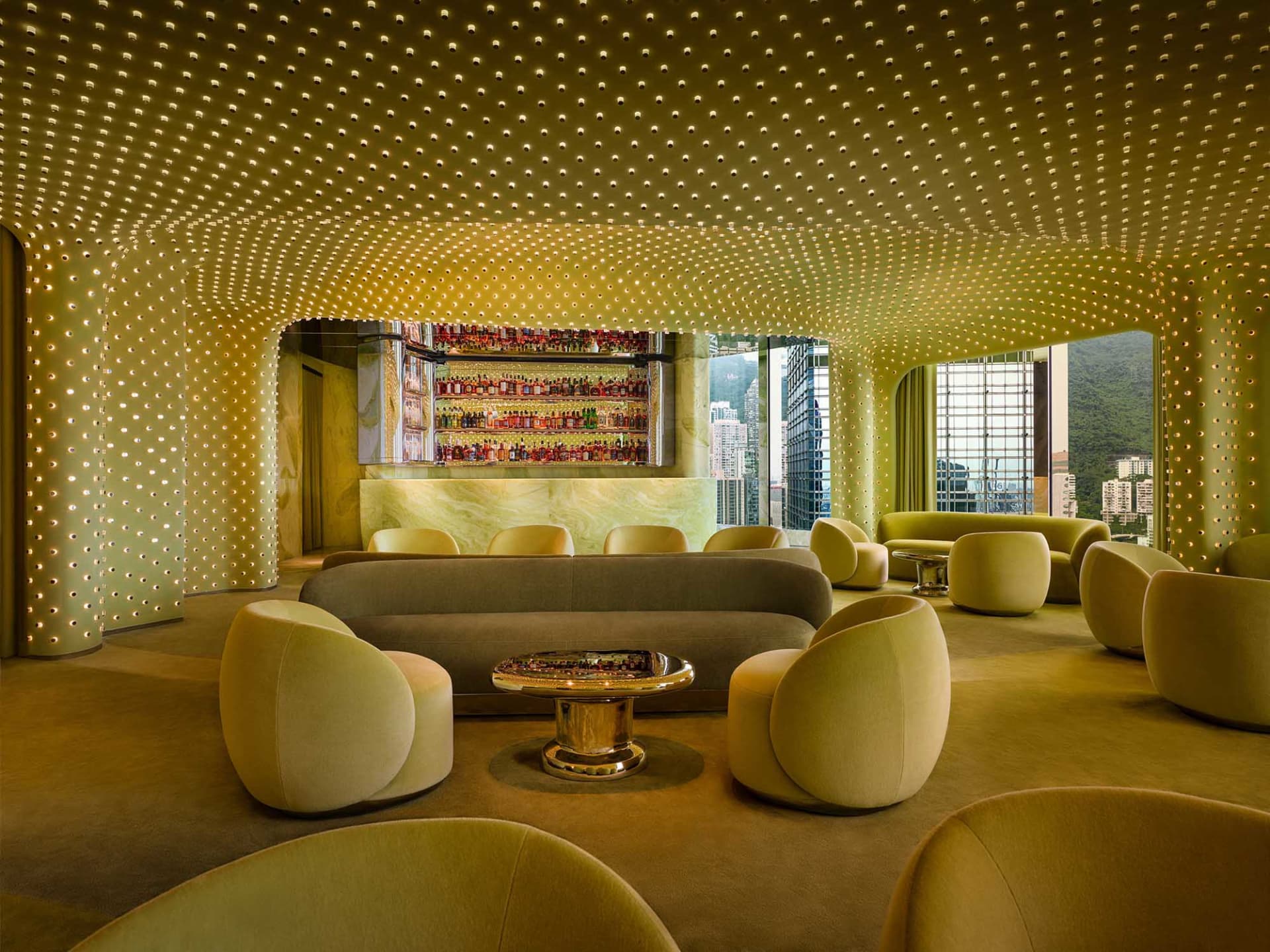Cozy modern lounge area with a bar, multiple seating options, and a warm ambiance created by natural and artificial light sources