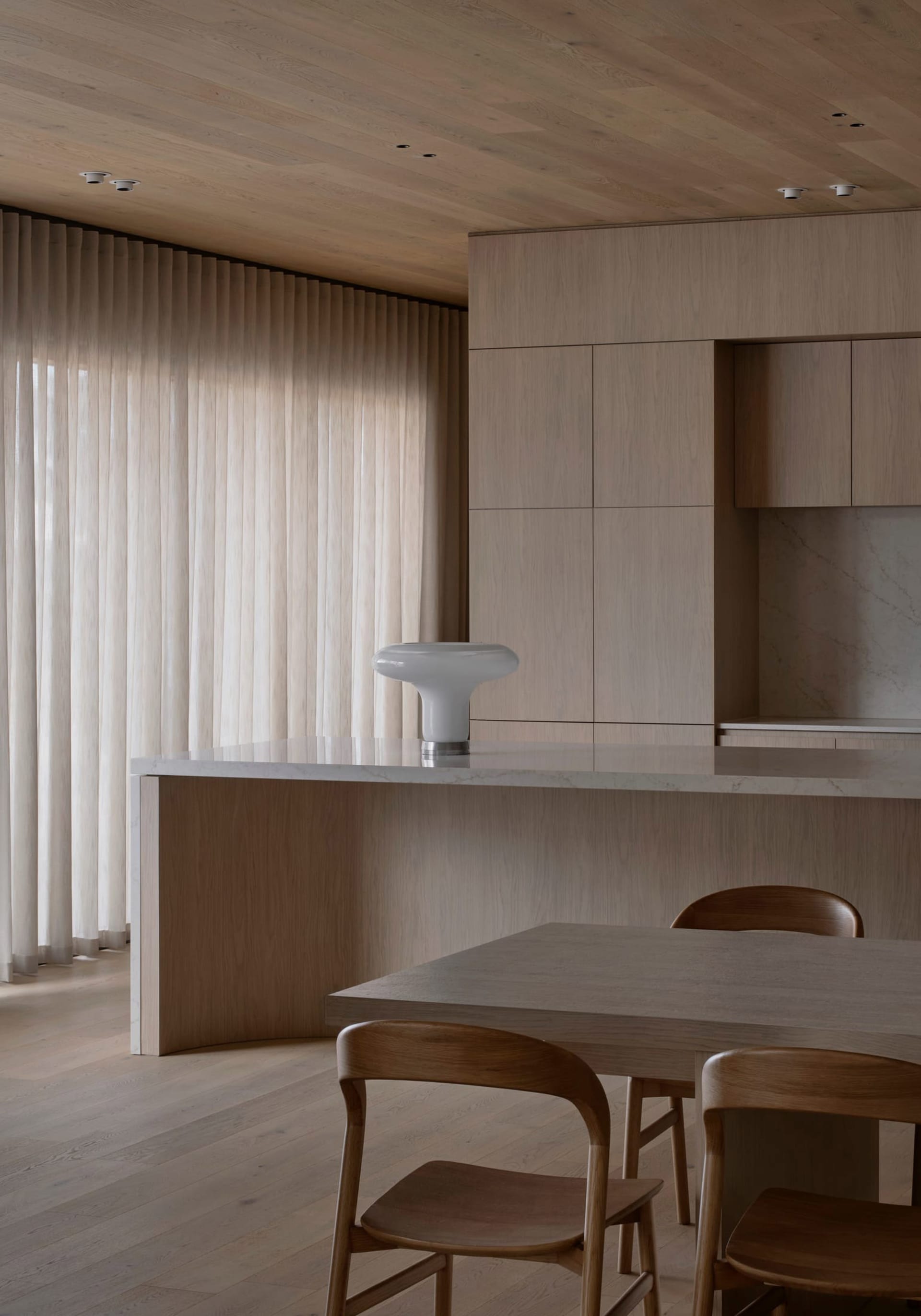 Cozy kitchen with wooden floors, a wooden table, and dim lighting, featuring a sink, refrigerator, and microwave