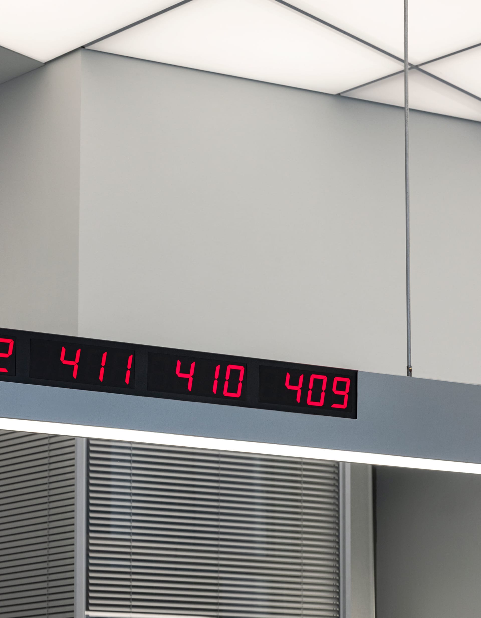 A minimalist room with a white color scheme, a digital clock mounted on the wall, and a sparse, empty space