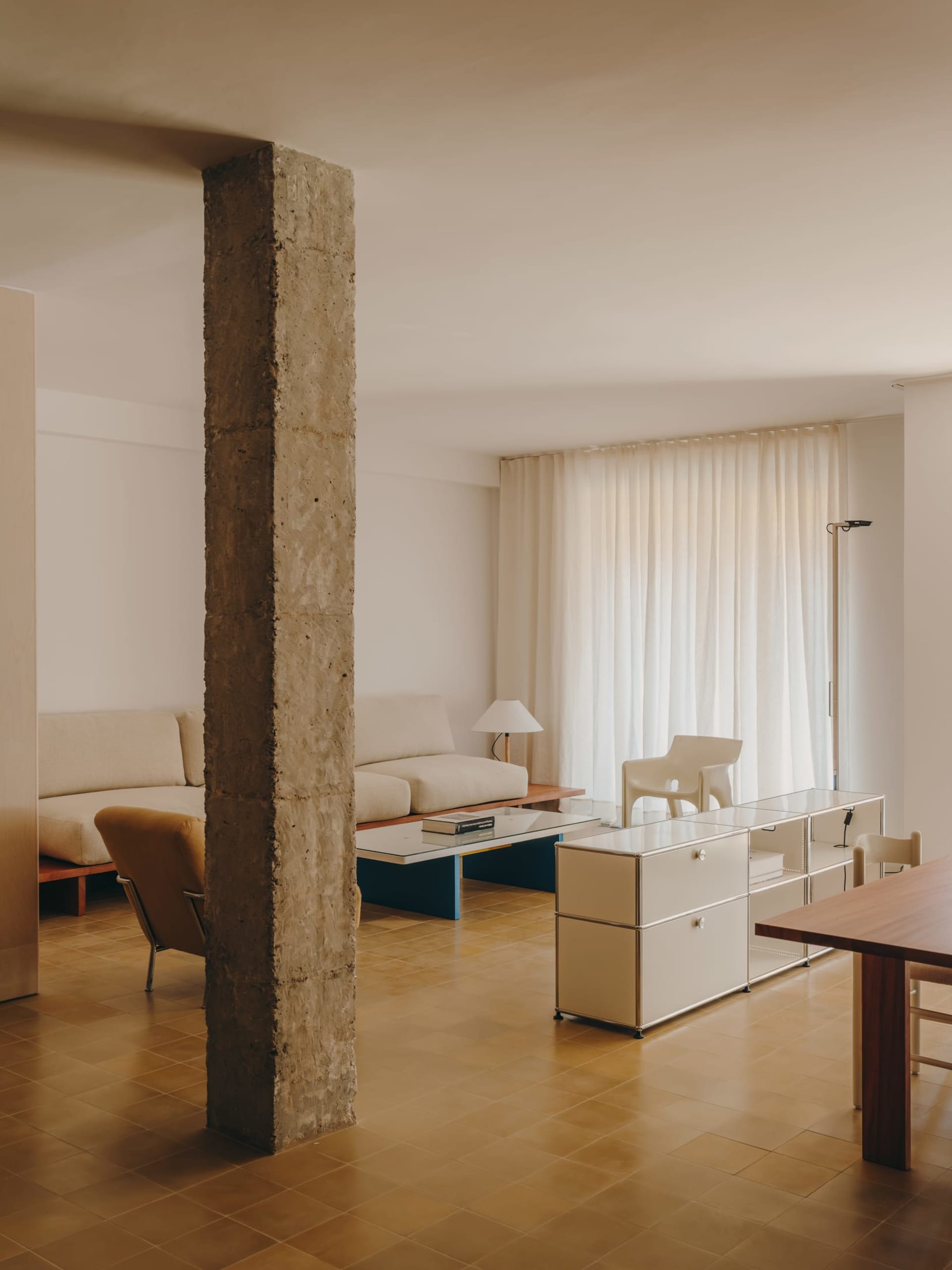 Comfortable living space with a couch, chair, dining table, and rug, lit by natural light from a window
