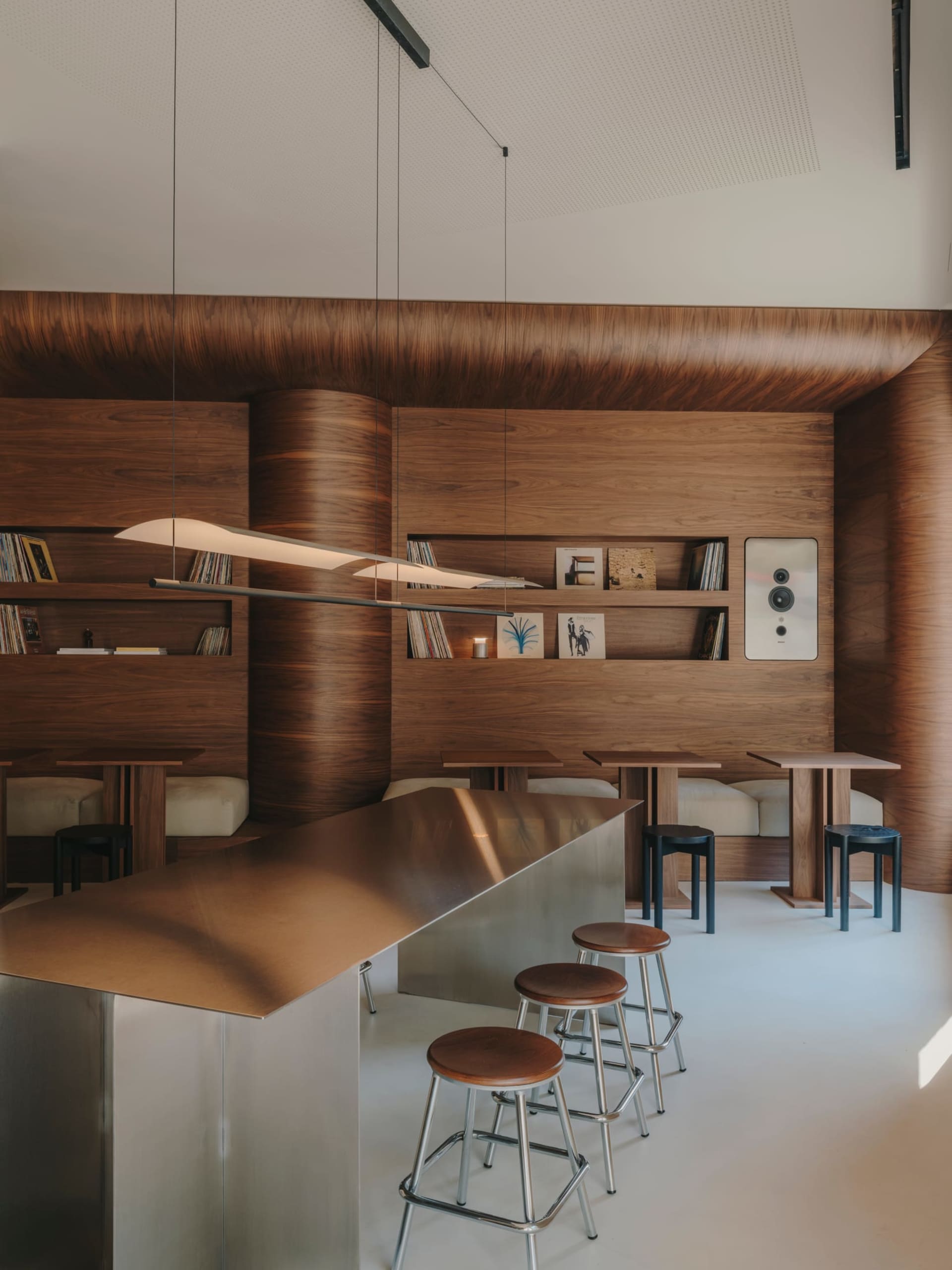 Warm and inviting restaurant with wooden walls, a bar area, and comfortable seating, featuring scattered books and a cozy atmosphere