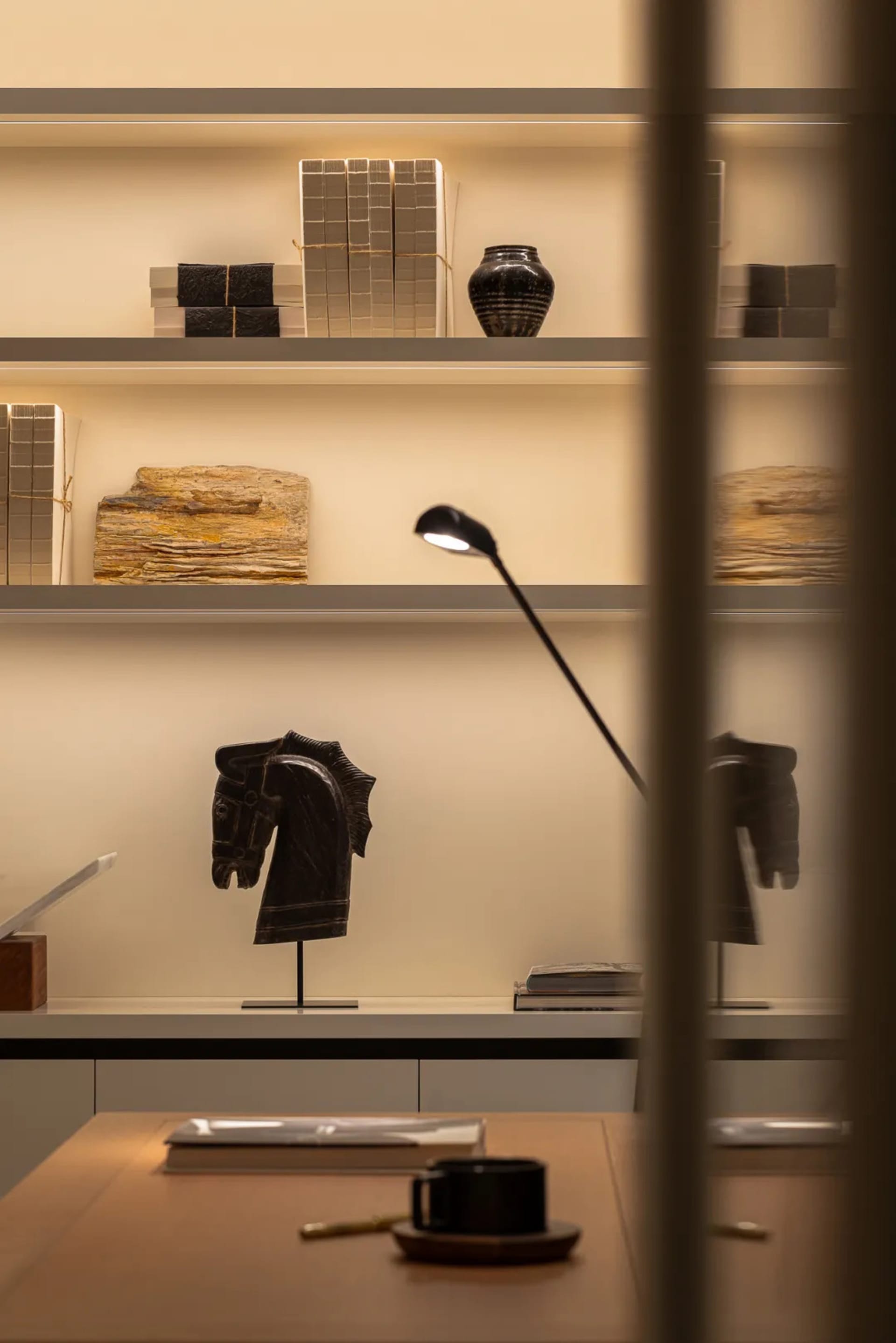 A retail space with white walls, a desk, and a light stand, showcasing books, vases, and clothing on display