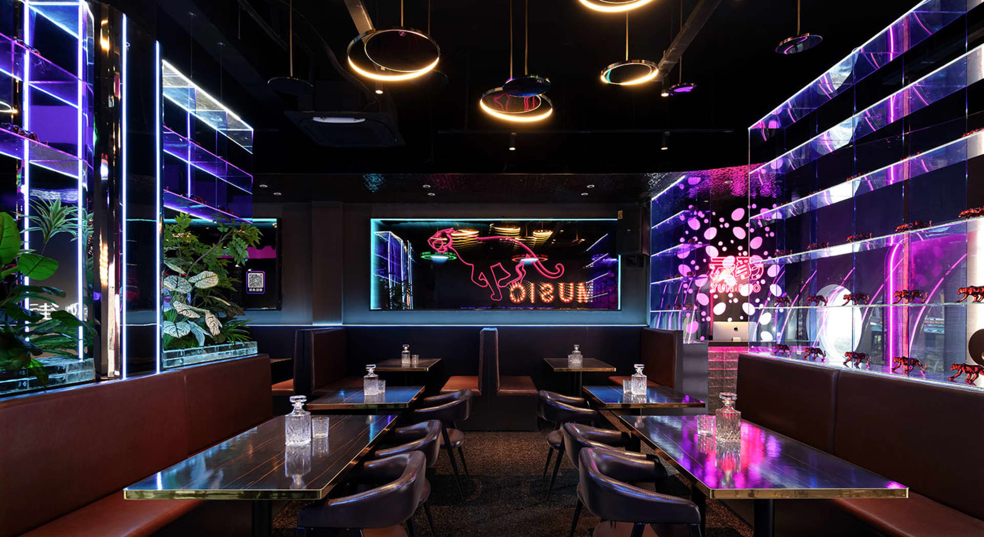 A modern restaurant interior with purple lighting, wood, and glass, featuring dining tables and chairs in a well-lit and inviting space