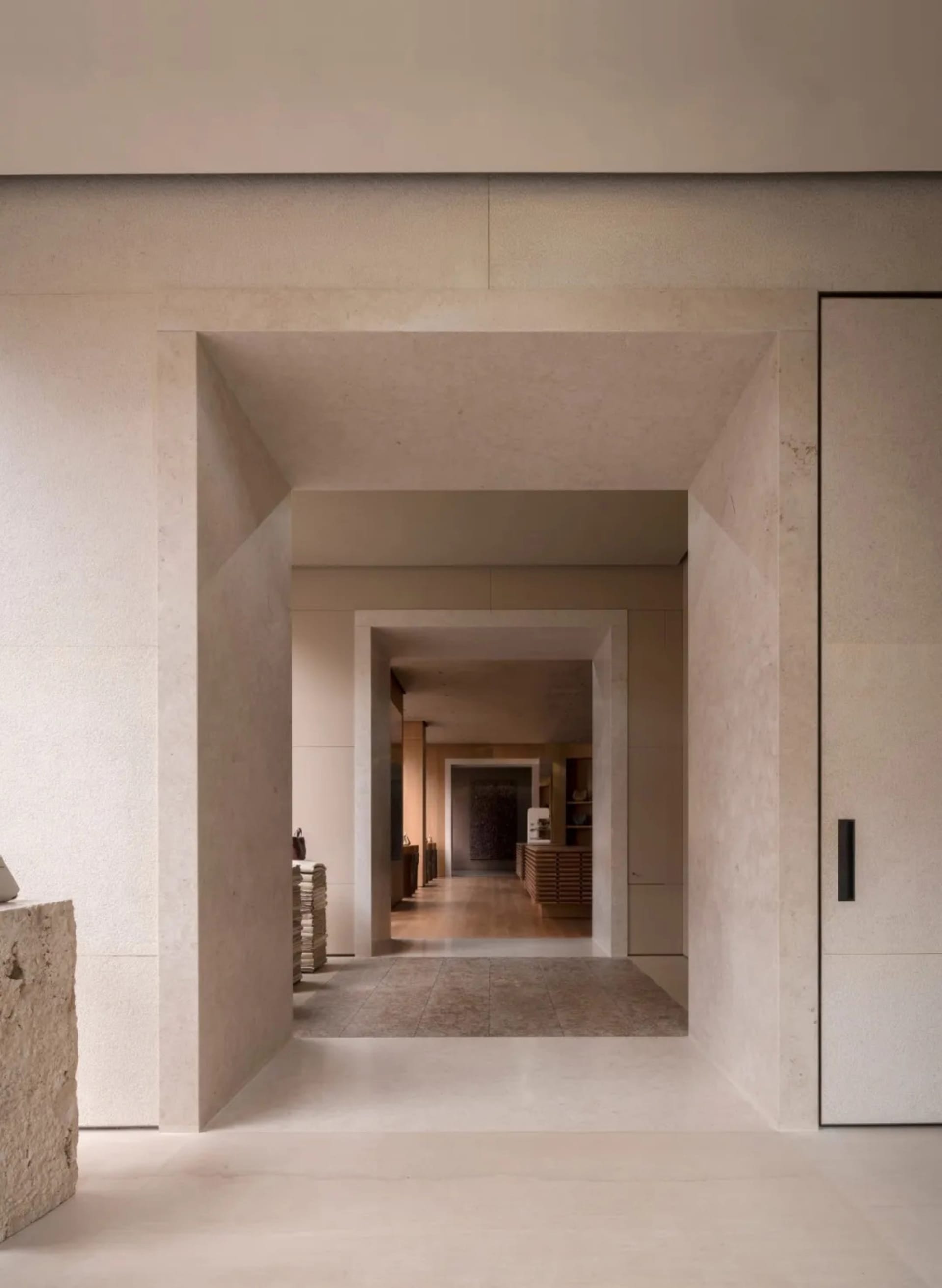 Narrow hallway with white marble floor, white walls, and dim lighting, featuring books on the floor