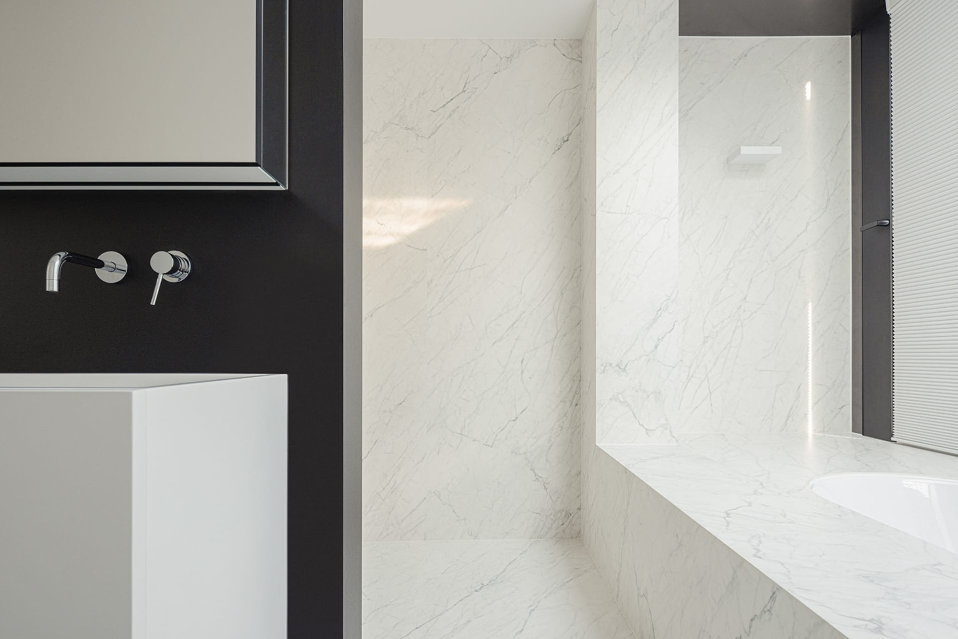 Bathroom with a white sink, marble countertop, and a white bathtub against a black wall, creating a luxurious and elegant atmosphere with dim lighting
