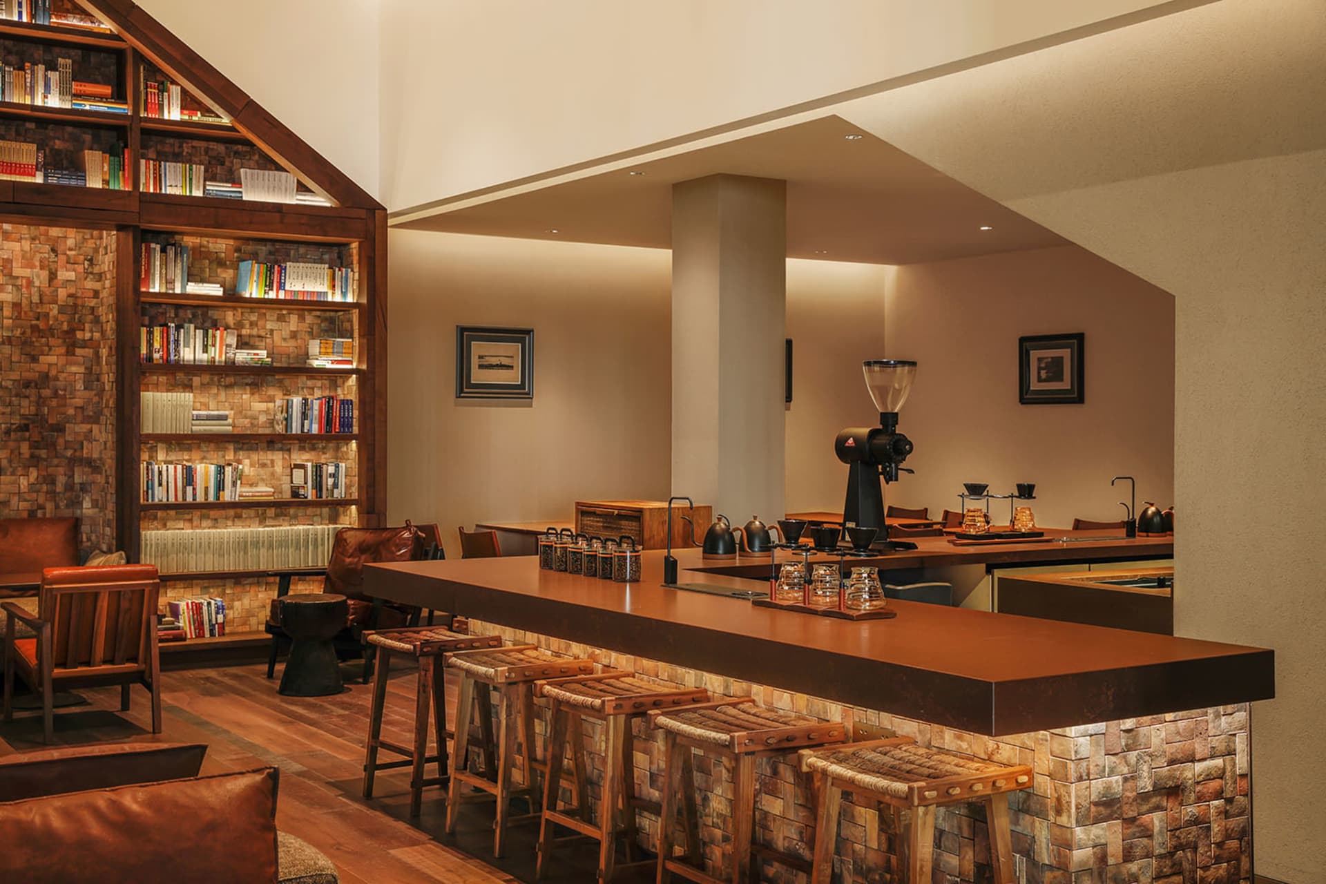 Cozy living space with a wooden floor, a wooden bar, and wooden stools, surrounded by books and a comfortable seating arrangement