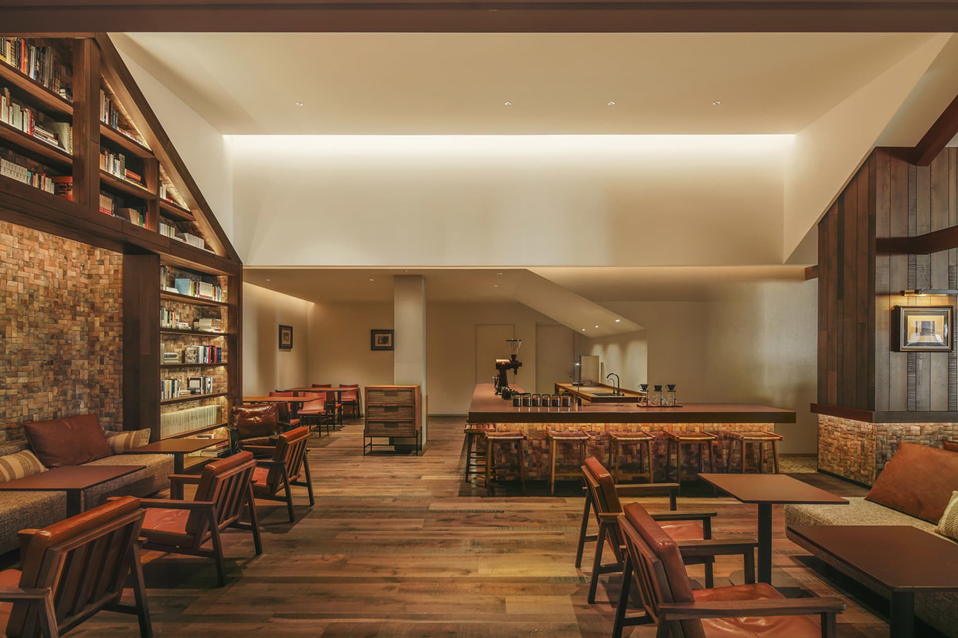Cozy restaurant with wooden floors, high ceiling, and a mix of natural and artificial lighting, featuring multiple seating options and a warm ambiance