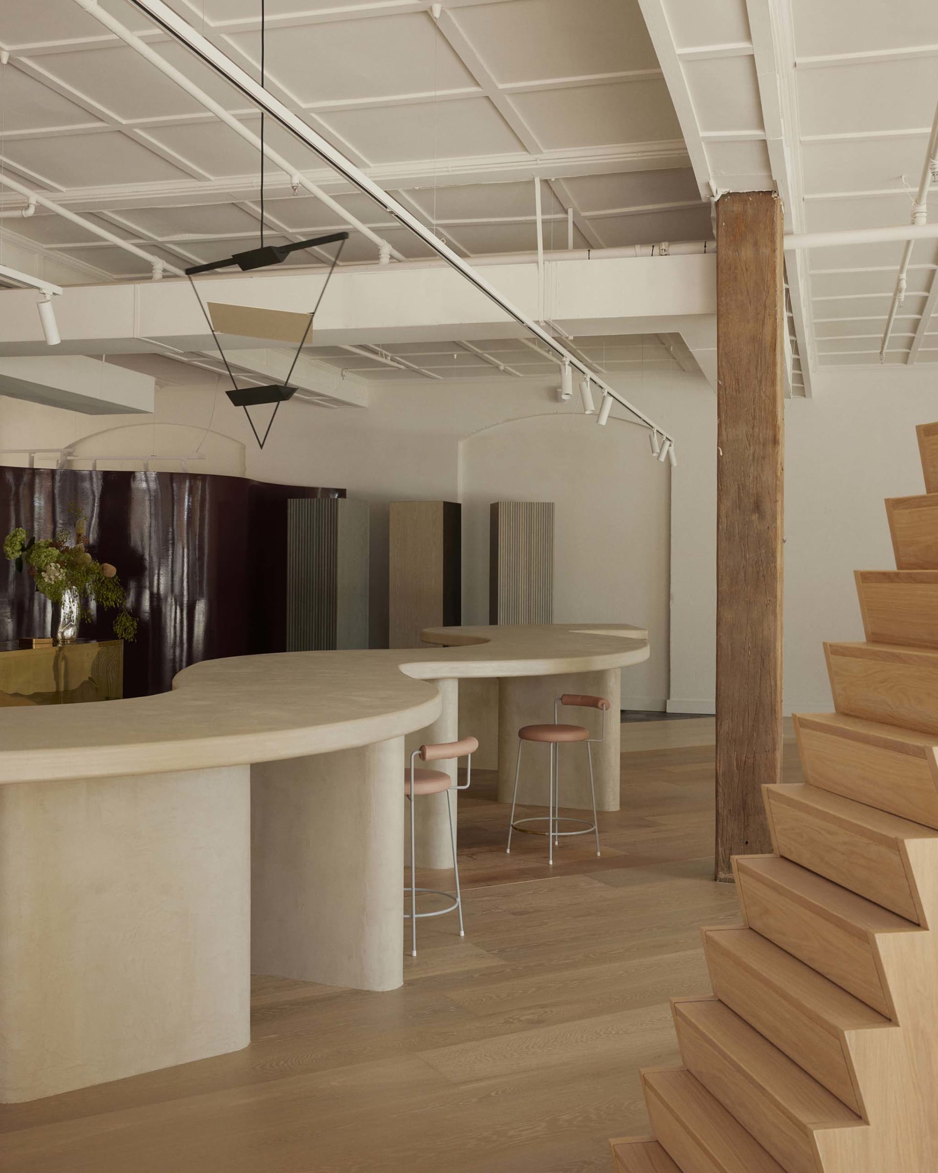 A modern kitchen and dining space with a marble counter, wooden floor, and stairs leading to a loft, set in a well-lit and inviting atmosphere