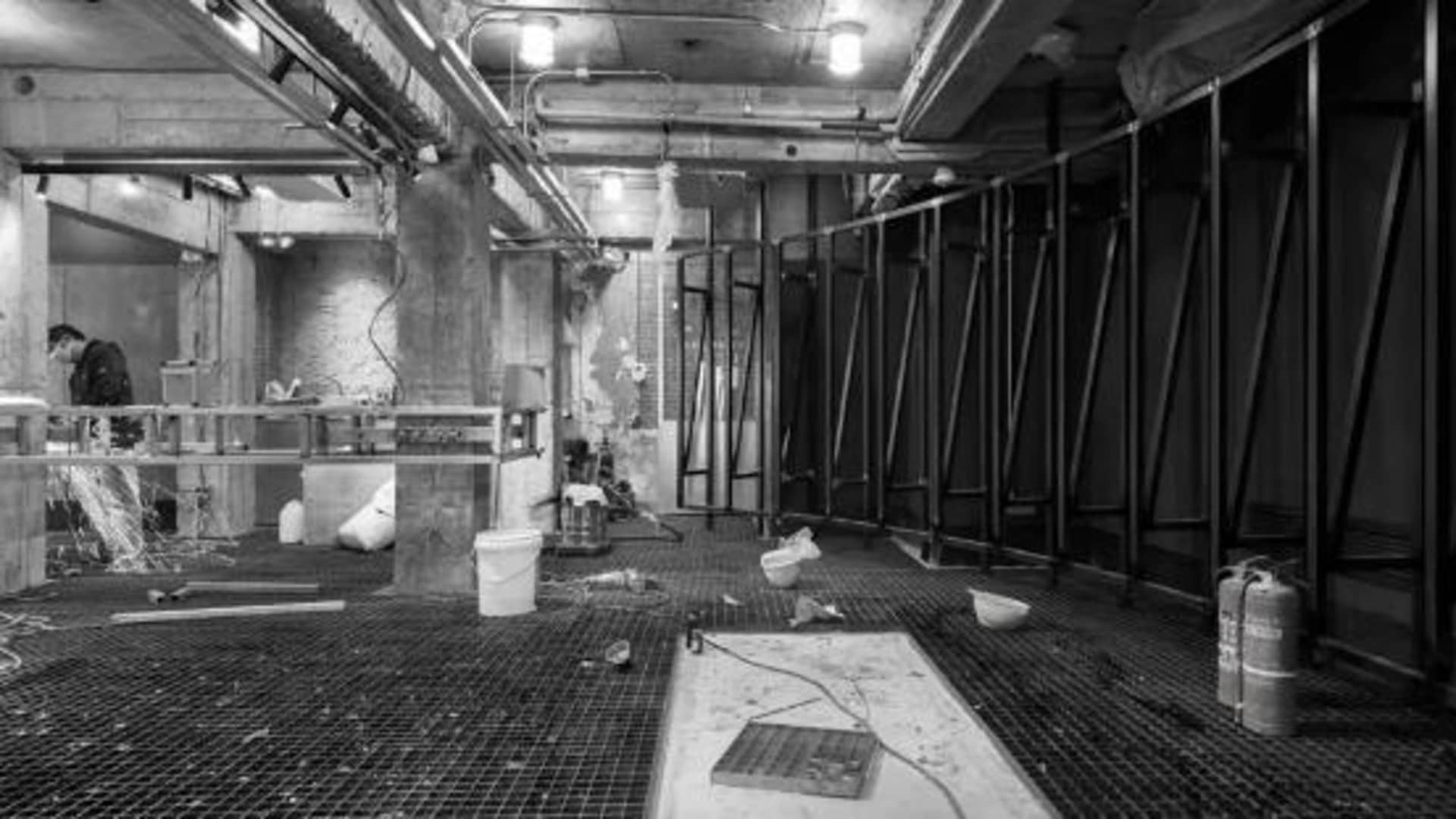 Dimly lit industrial bathroom with two toilets and a cement floor