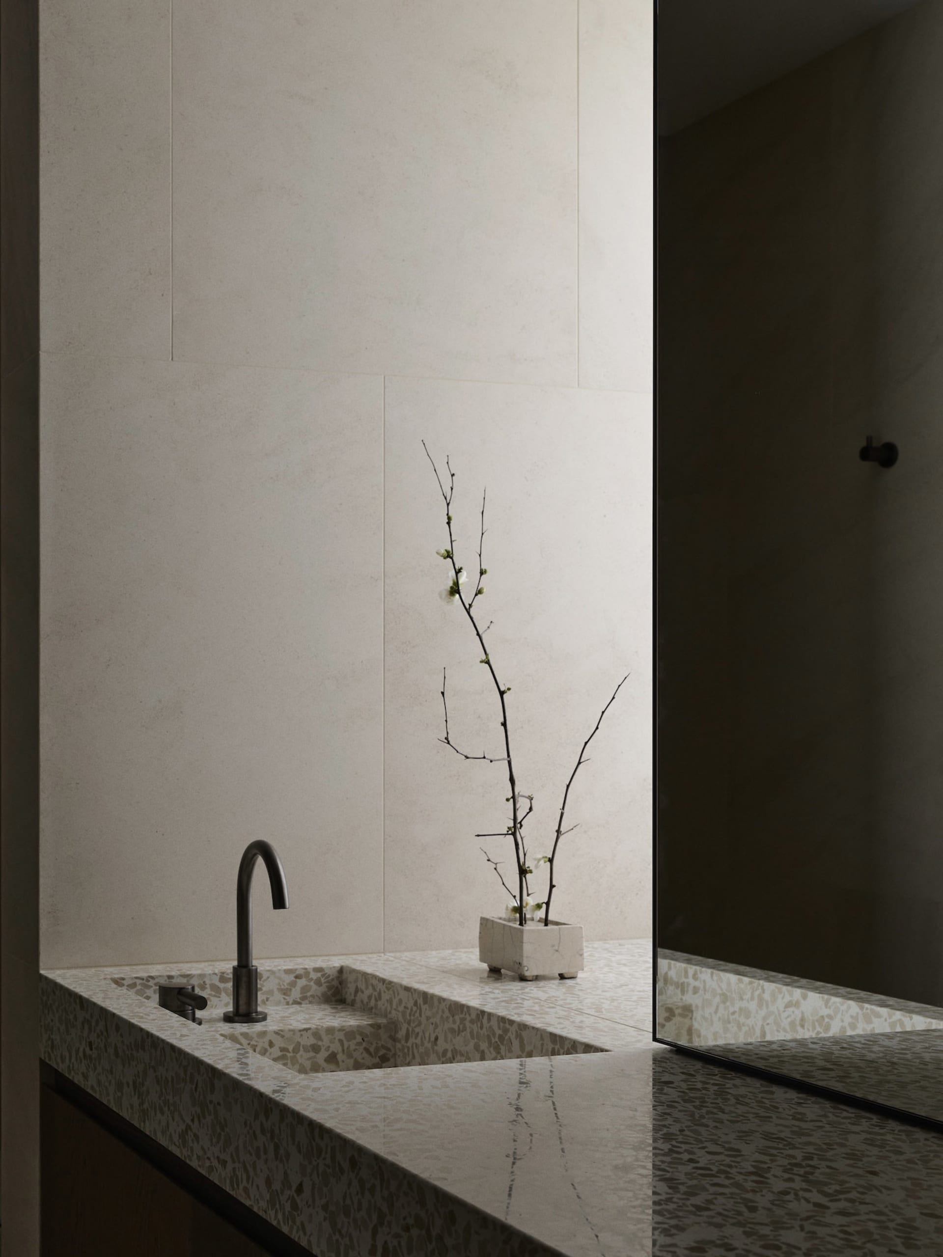 A modern bathroom with a sink, mirror, and potted plant, featuring marble and glass surfaces, in a well-lit space