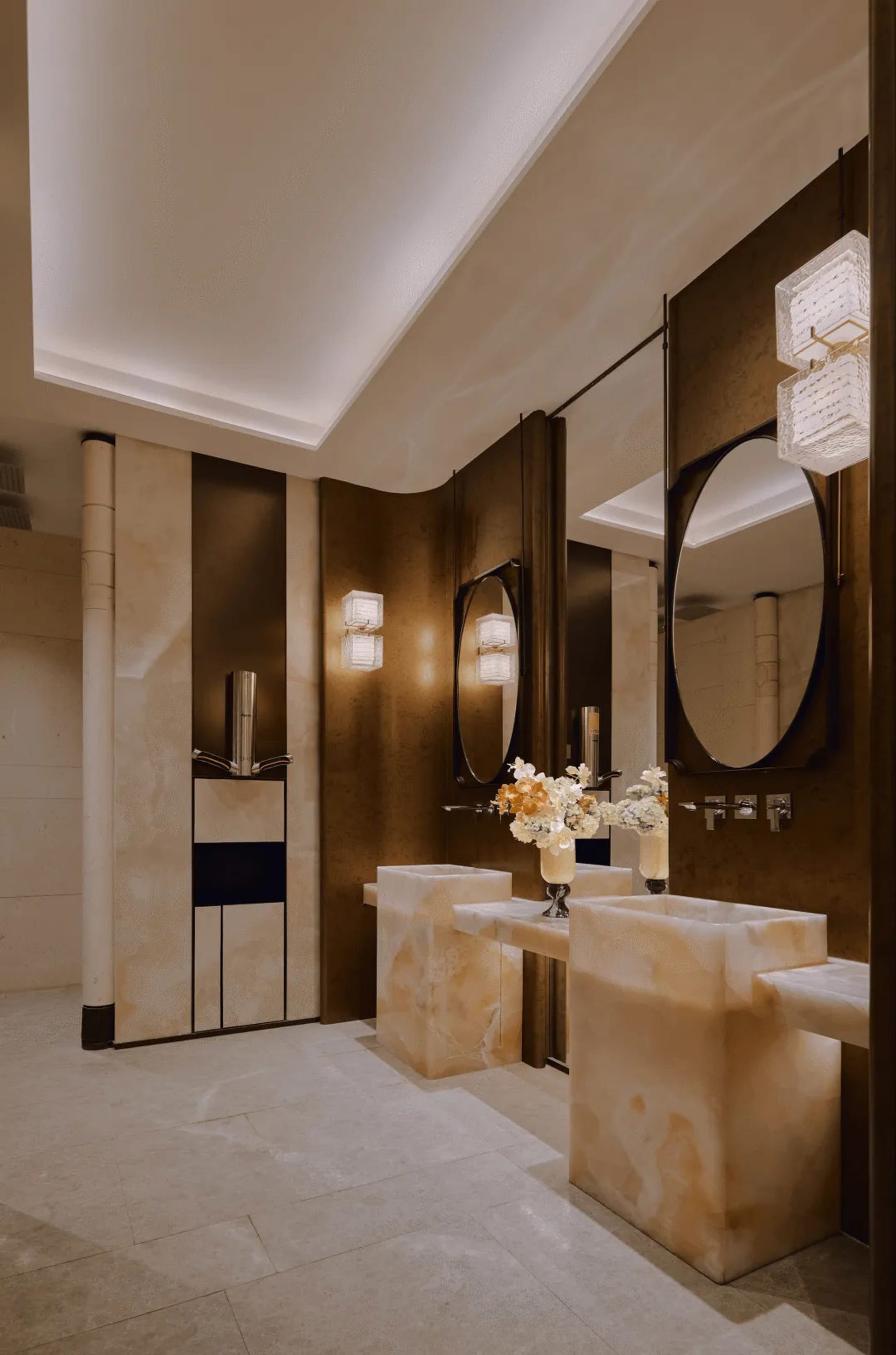 Modern bathroom with brown marble walls, a large mirror, a sink, and a toilet, with dim lighting creating a cozy atmosphere
