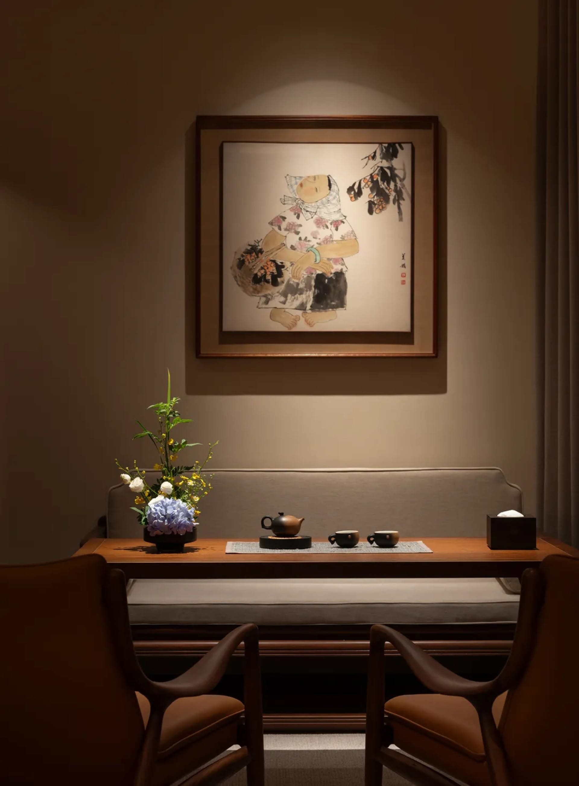 A cozy living room or dining area with a wooden table, chairs, couch, and chair, set with cups and a vase, creating a warm and inviting atmosphere
