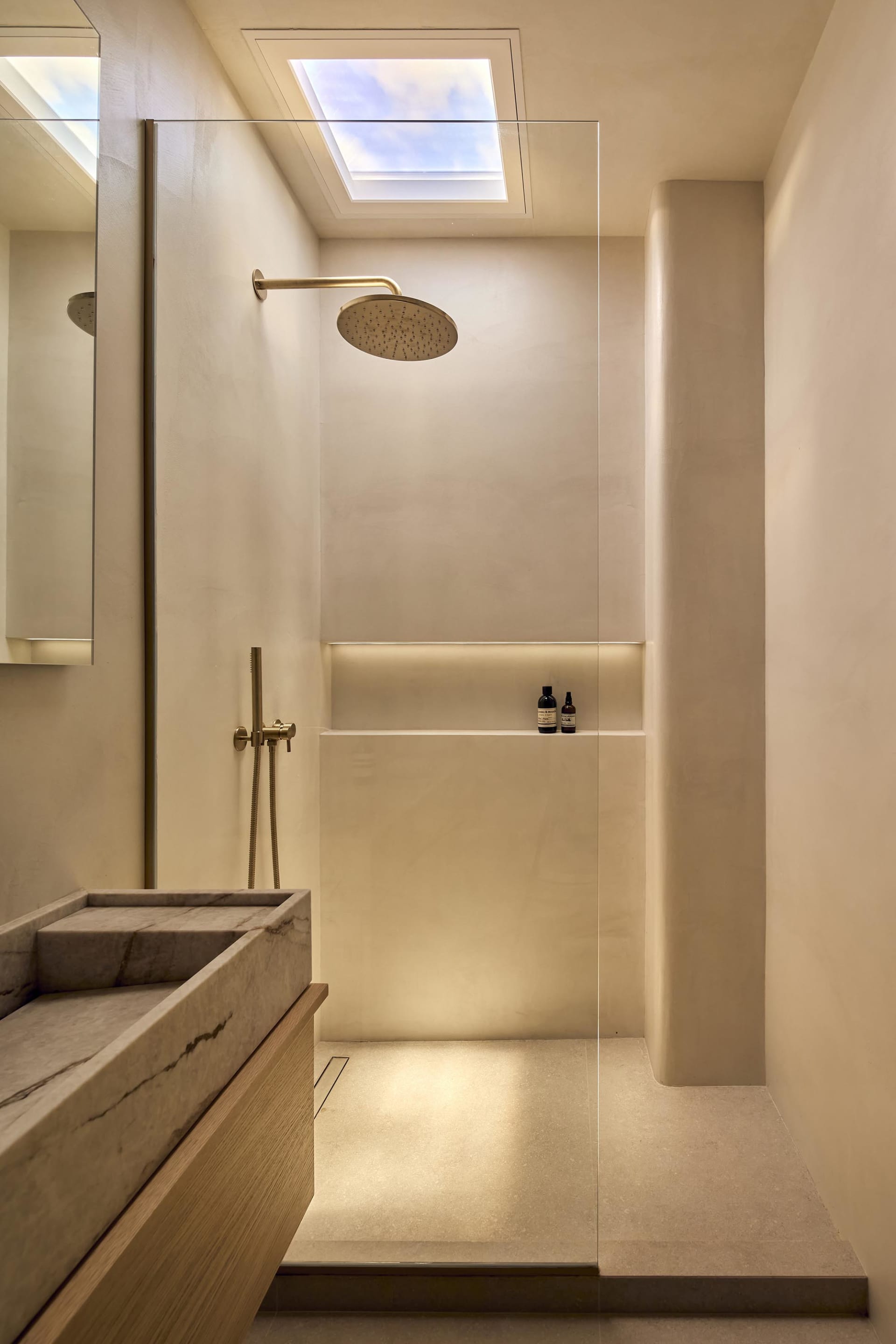 Modern bathroom with a white color scheme, featuring a marble sink, a gold shower head, and a clean, elegant appearance