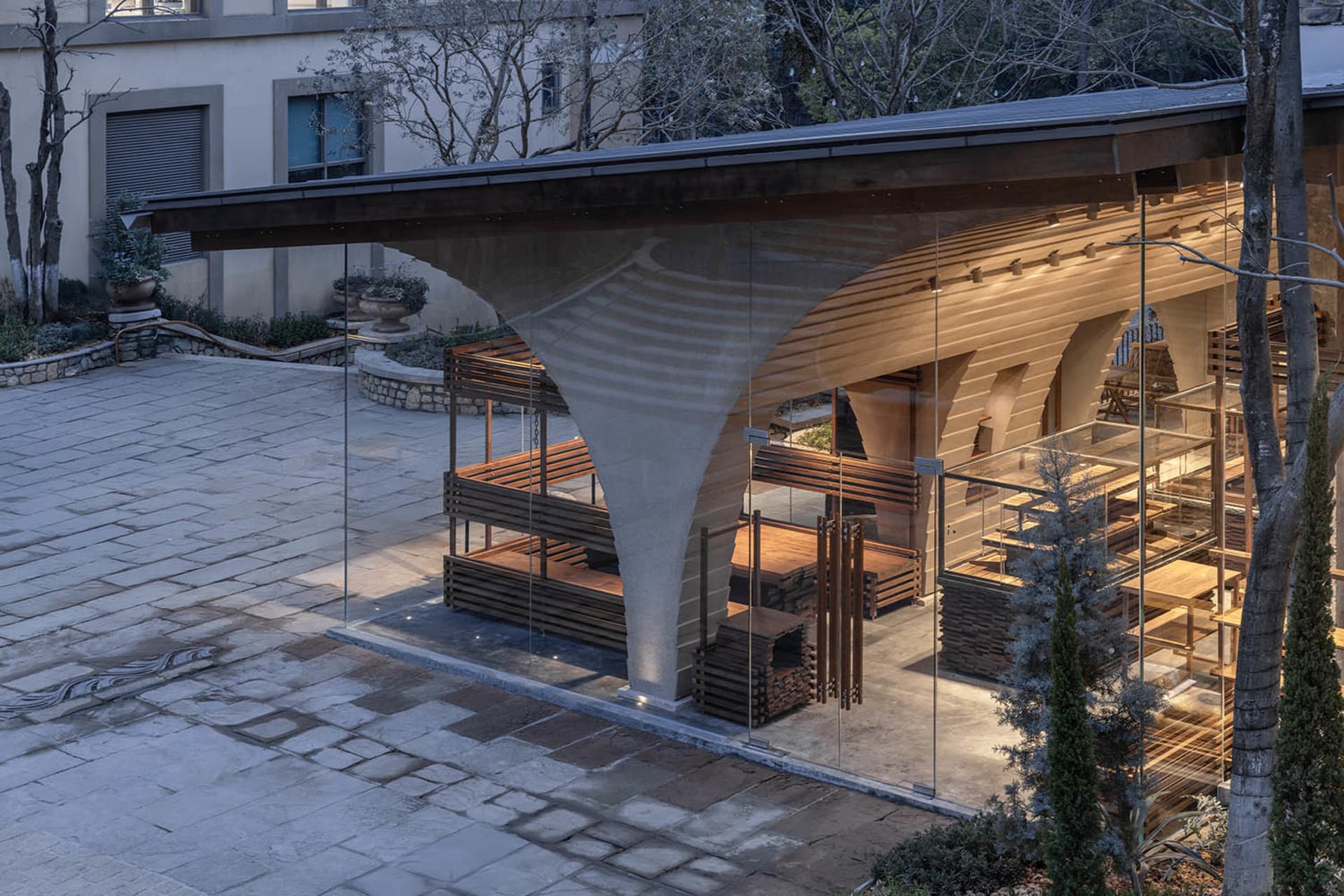 一間現代的居住空間，具有木地板、玻璃牆和自然光線，展示著餐廳區域和家具
