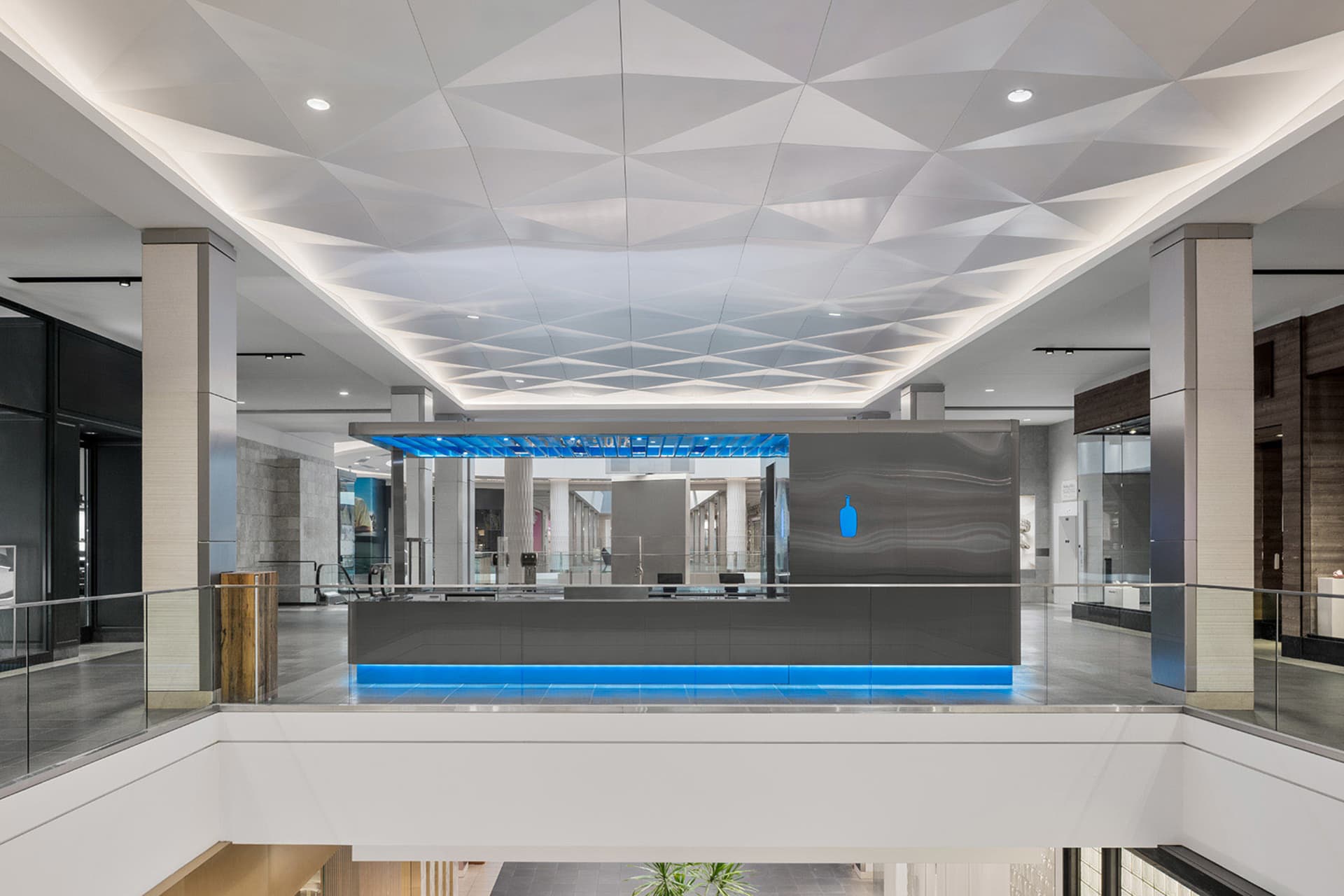 A bright and welcoming office space with a blue and white color scheme, featuring a large open lobby with a blue counter and large window, illuminated by natural light
