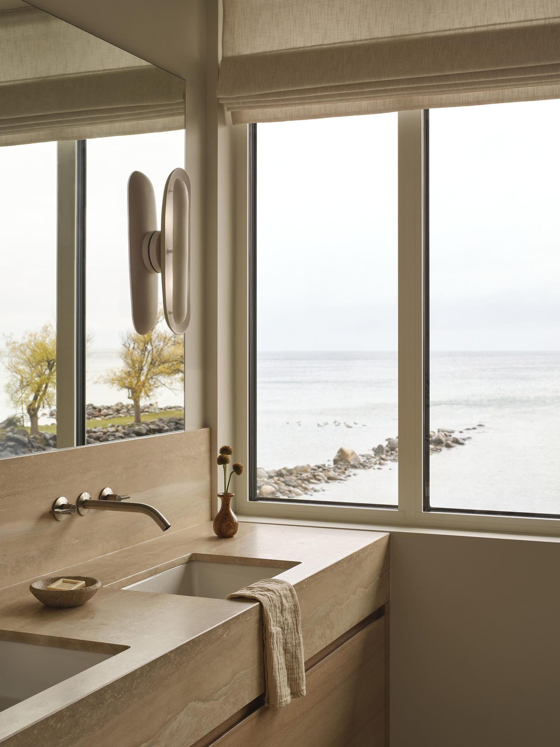 A modern bathroom with a sink on the left and a large window on the right, featuring a clean and organized space with a towel on the window sill