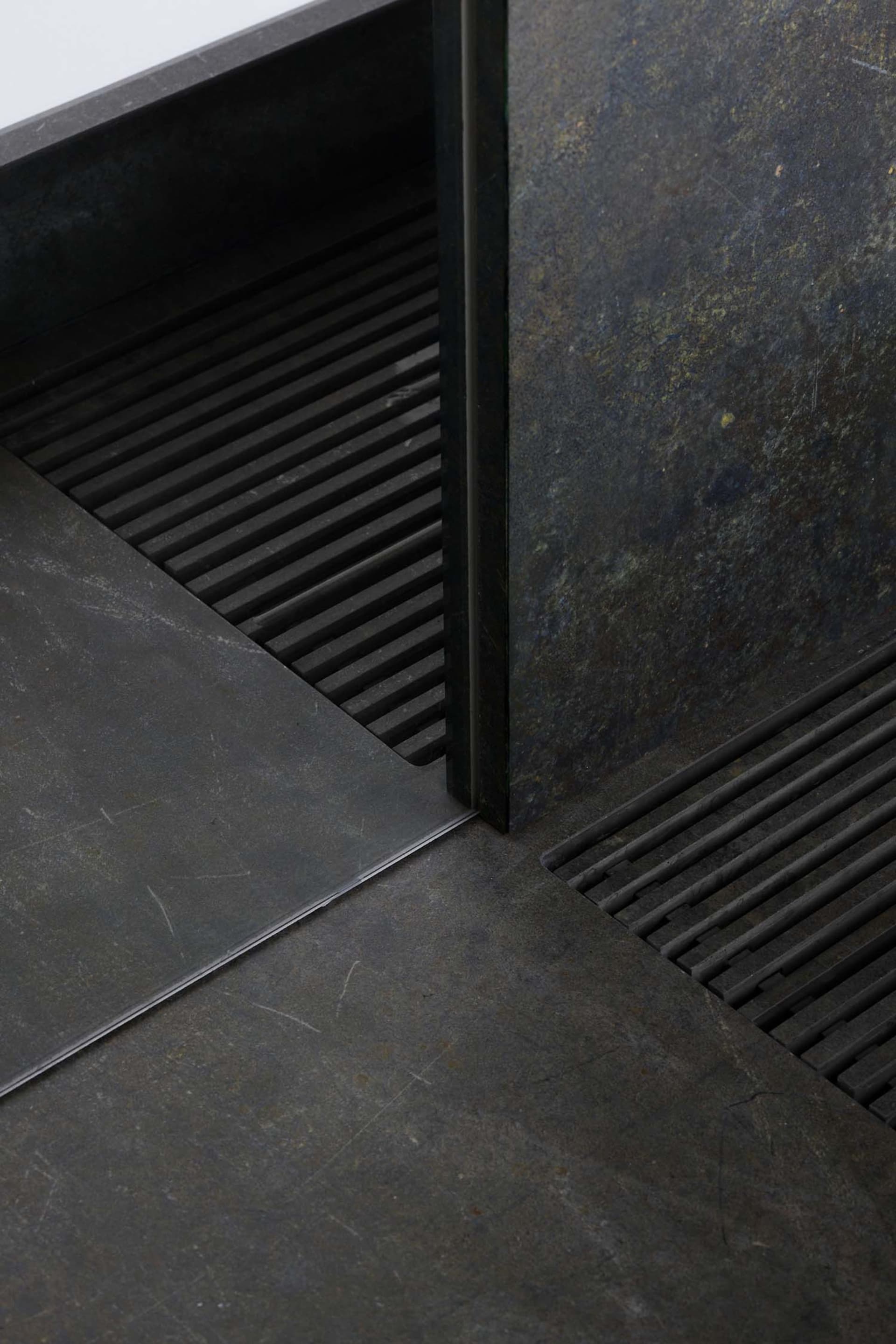 A metal staircase with a metal door at the bottom, set in a commercial or industrial space