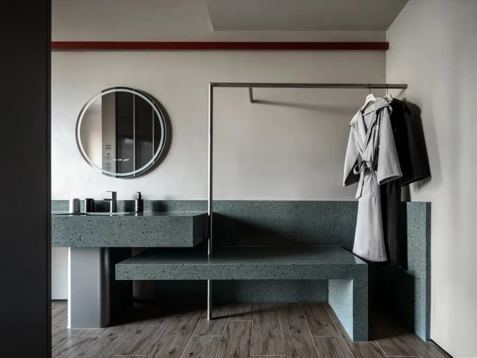 Modern bathroom with a stone bench, mirror, and coat rack, well-lit with clean lines and functionality