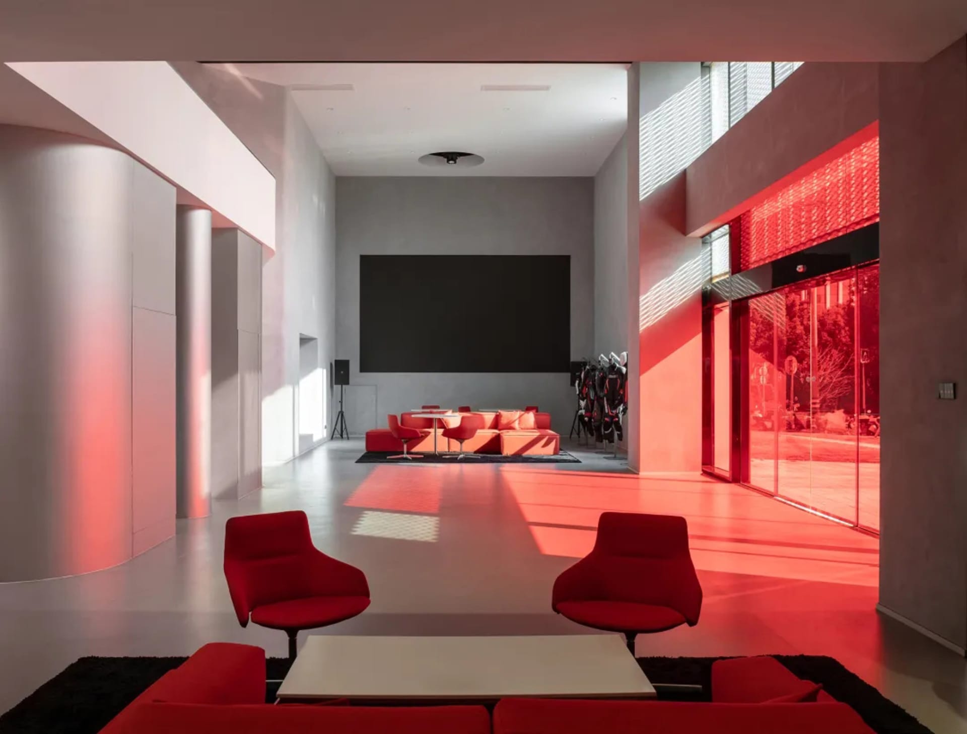A well-lit living room with a red couch, chair, and TV, surrounded by furniture in a warm and inviting atmosphere