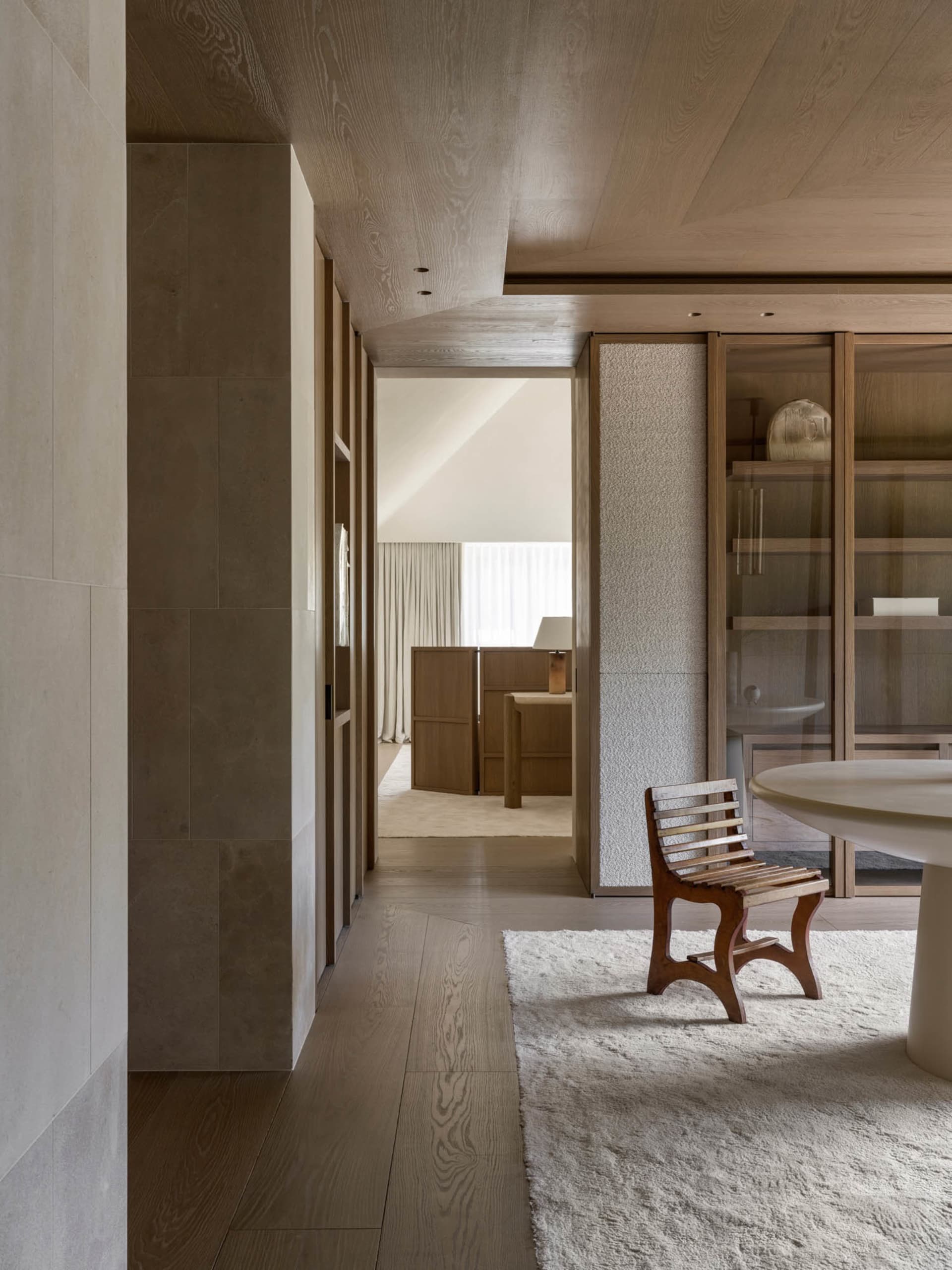 Cozy living room with a wooden floor, a chair, a dining table, and a couch, well-lit with natural light from the windows