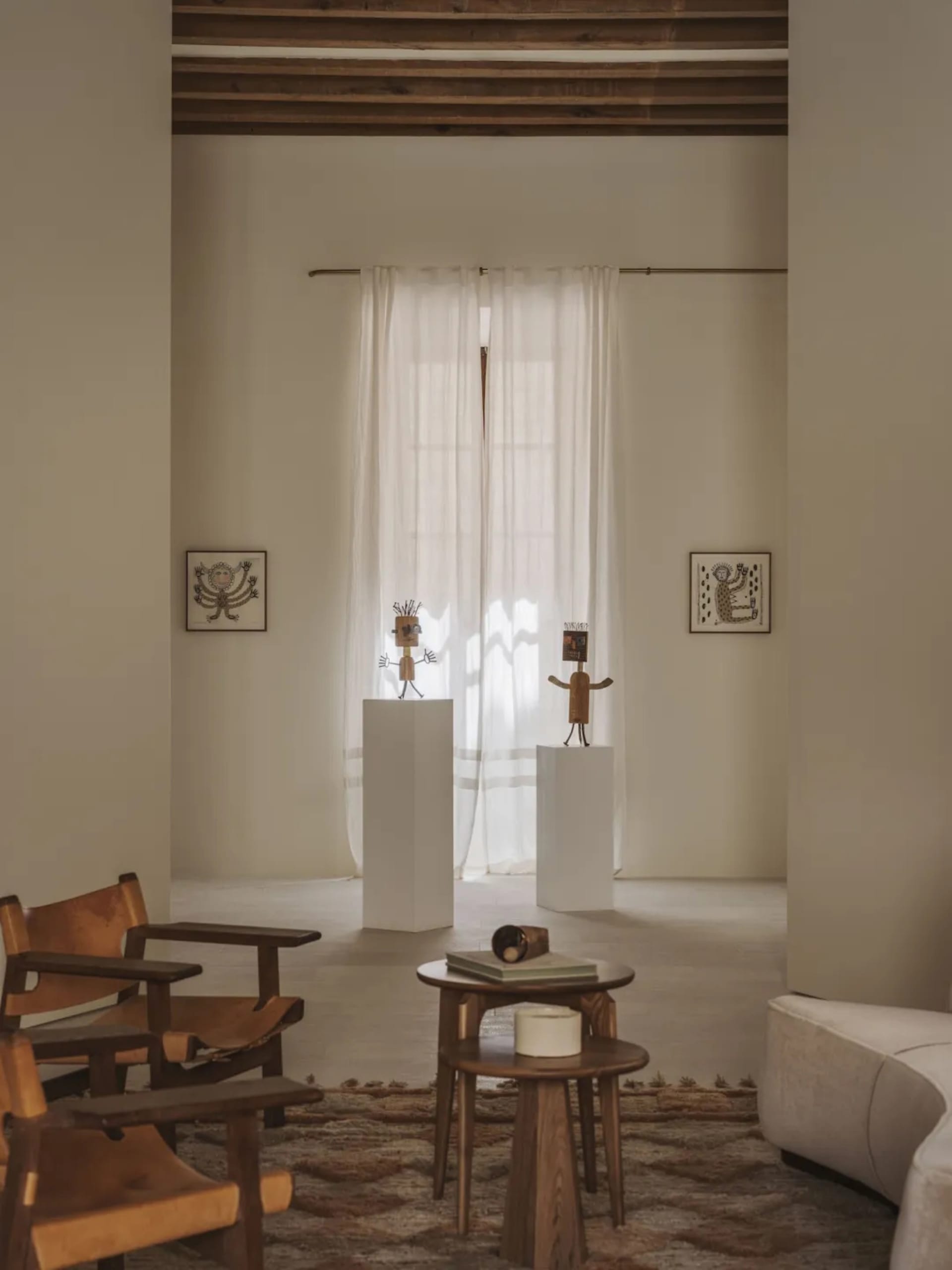 A modern living room with a white color scheme, a couch, a chair, a dining table, and decorative items, connected to a dining area with a dining table and chairs, in a well-lit space with a comfortable and inviting atmosphere