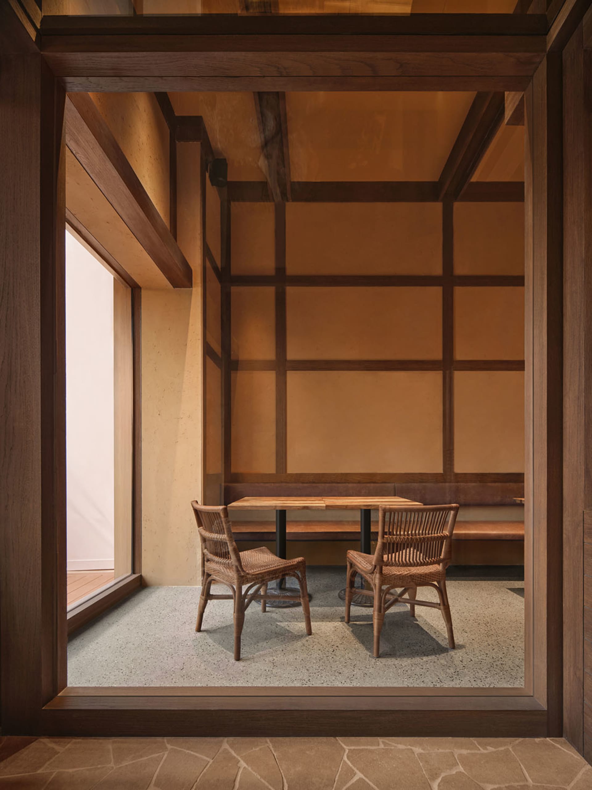 A warm and inviting dining area with a wooden floor, a dining table, chairs, and a bench, lit by natural sunlight