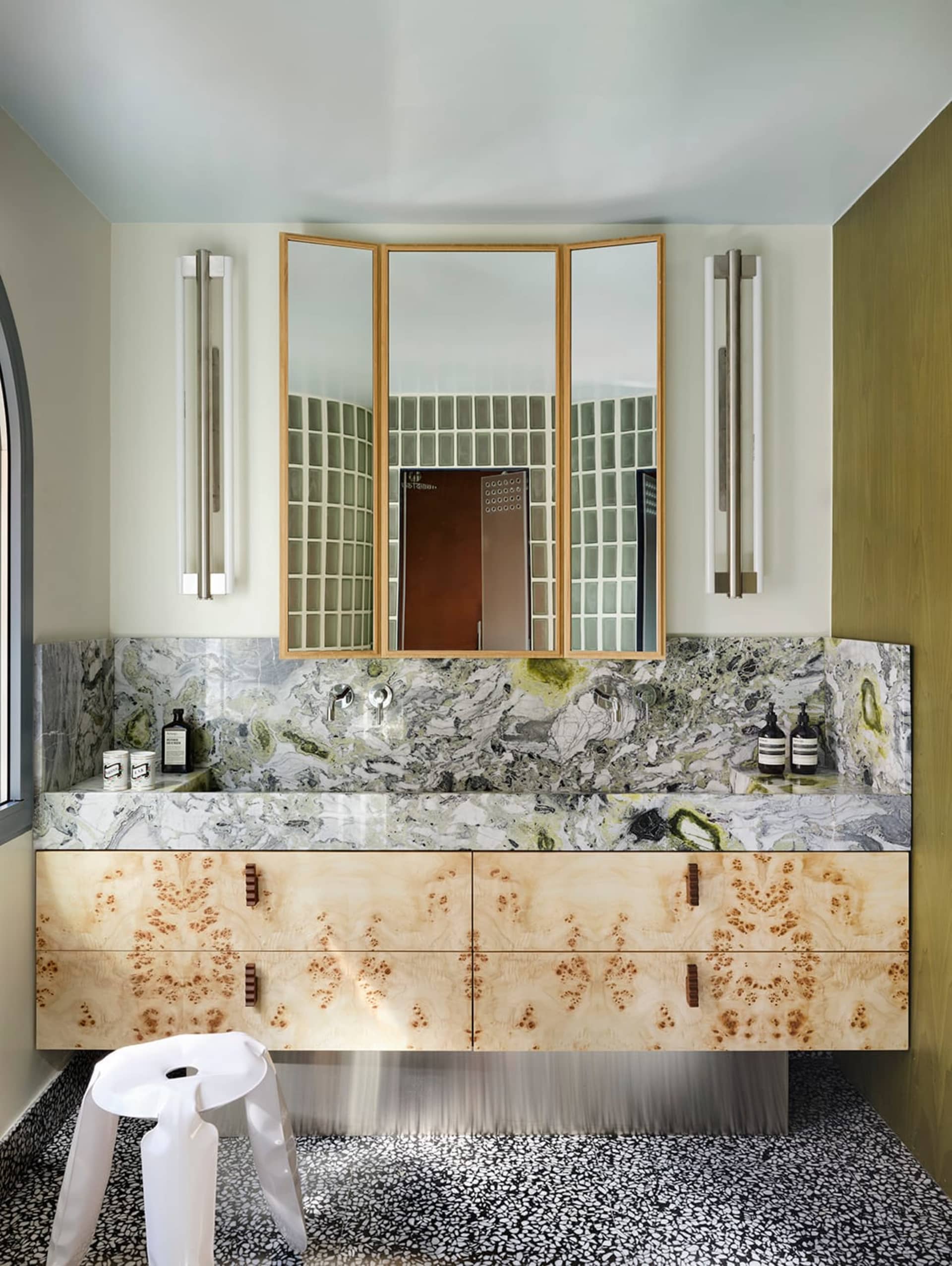 Bathroom with a marble countertop, sink, mirror, and toilet in a dimly lit space