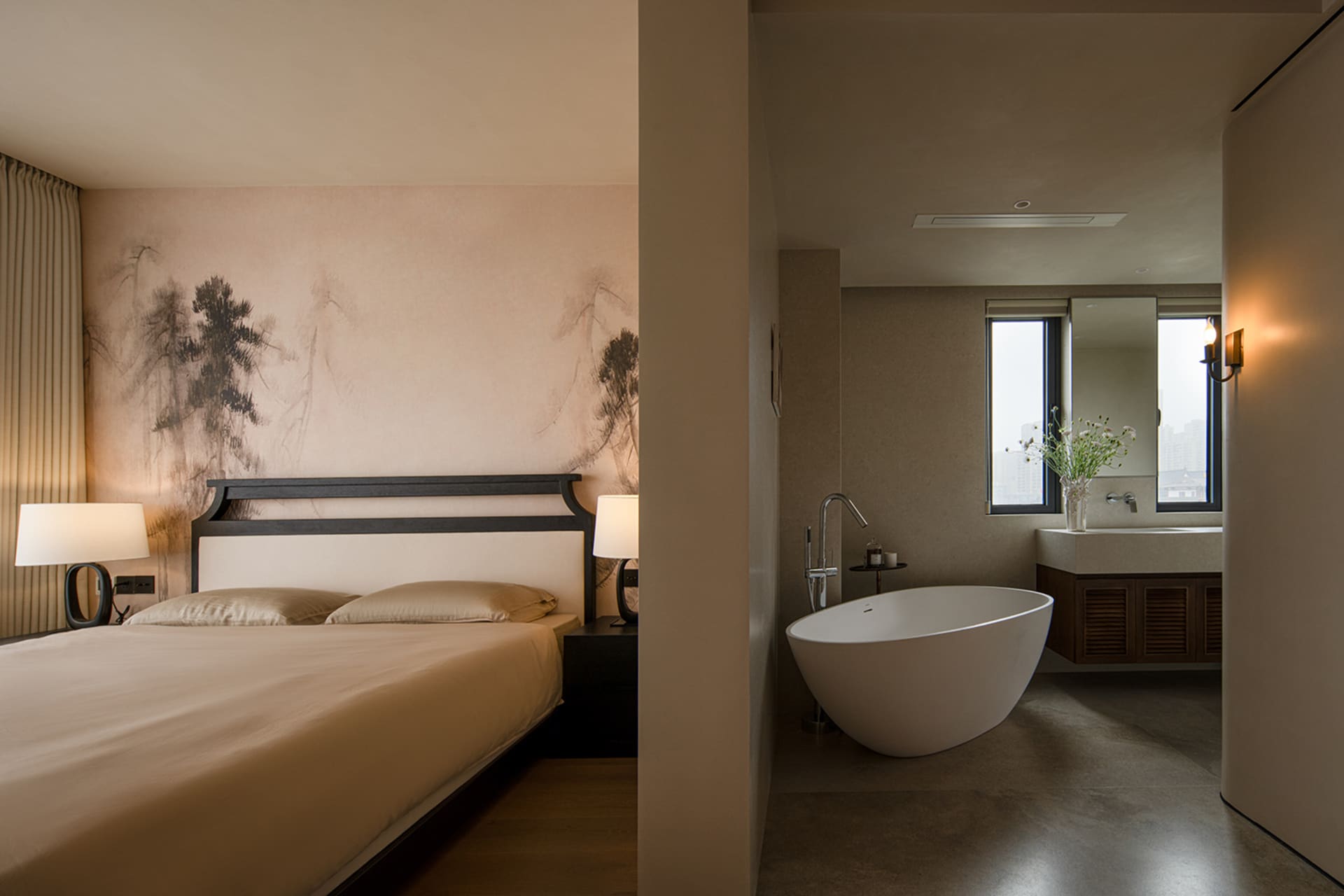 Bedroom with a brown color scheme, Asian-style paintings, a bed against the wall, and a bathtub near the window in a dimly lit space