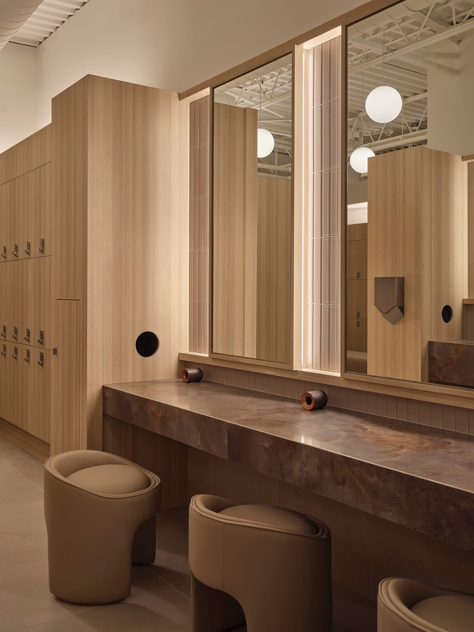Bathroom with wooden walls, a wooden bench, and a large mirror reflecting the sink and interior