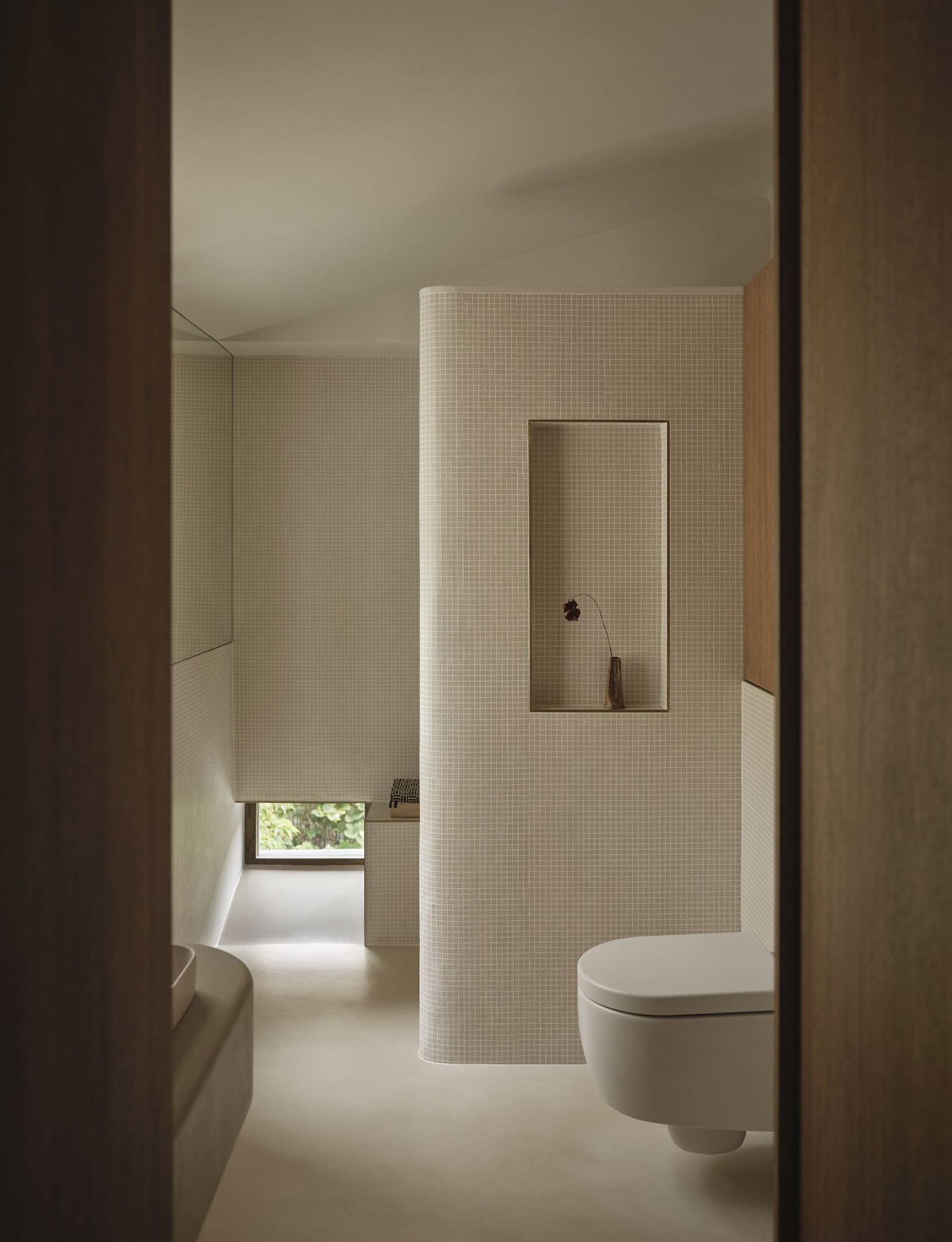 A well-lit bathroom with a white toilet, sink, and mirror, positioned in a typical layout