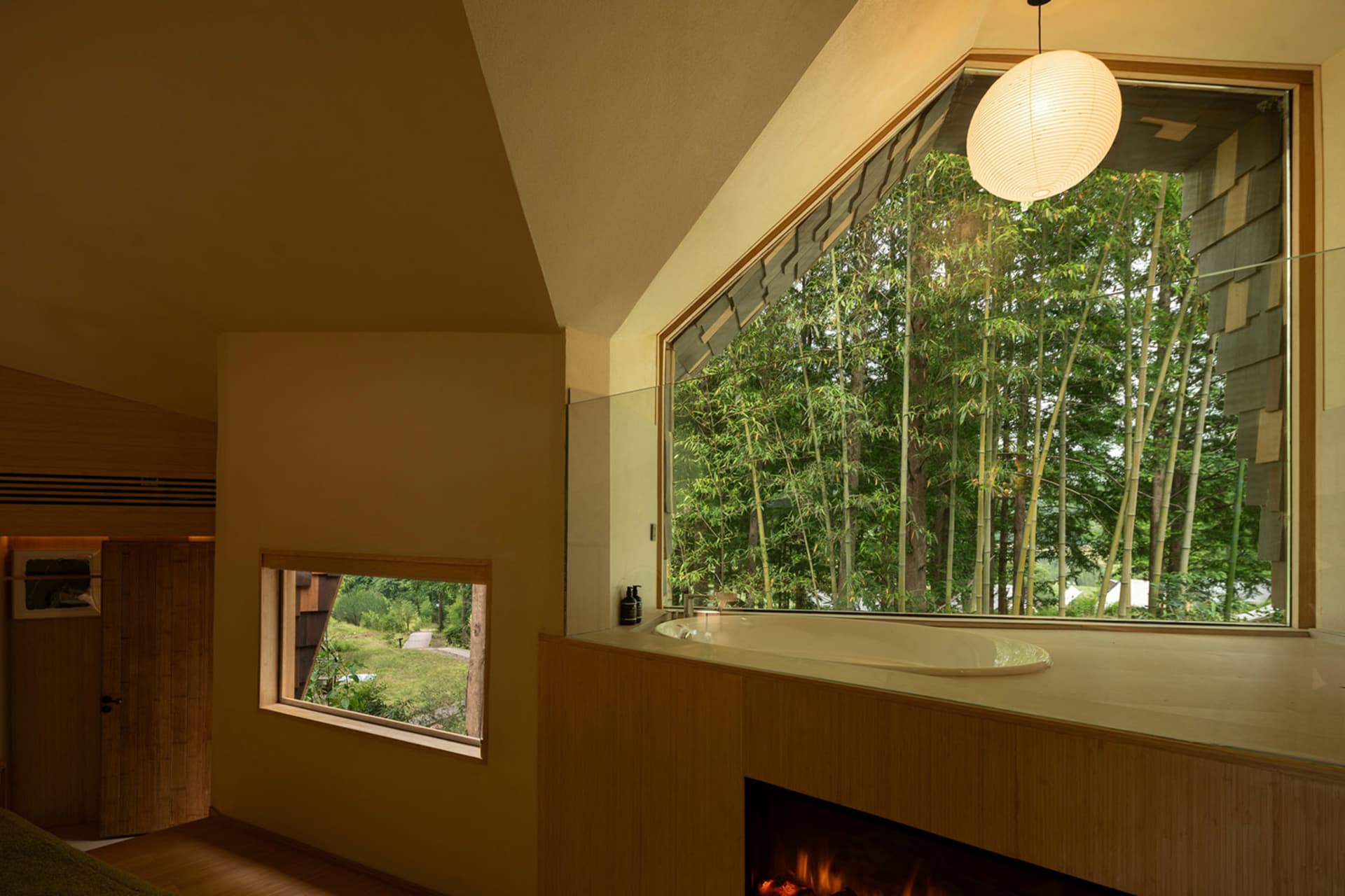 Well-lit bathroom with a wooden design, a large window, a bathtub, and a fireplace, creating a cozy and inviting atmosphere