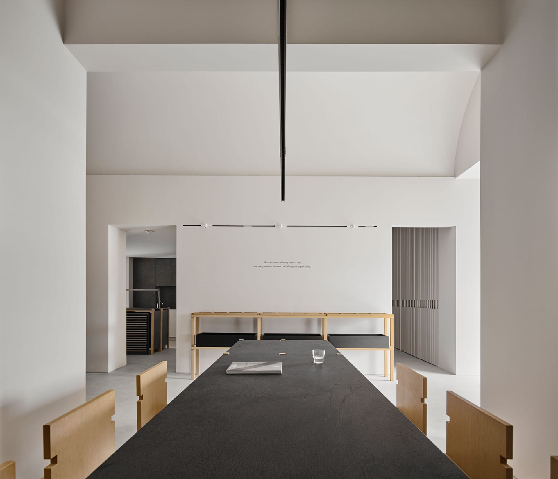 A large, open dining room with a modern design, white walls, and soft lighting, featuring a dining table and chairs, and a vase on the table