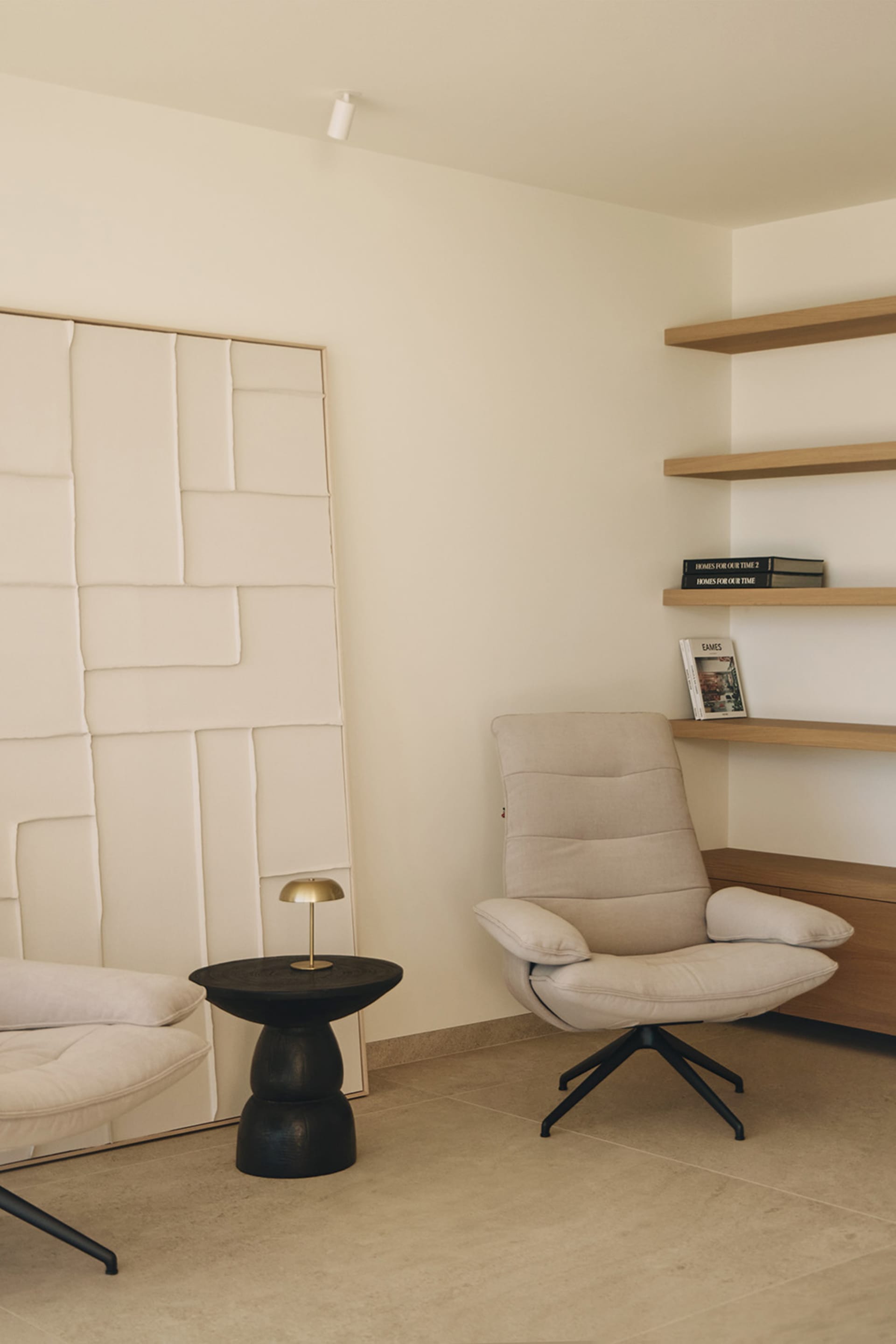Cozy living space with a white chair, couch, and bookshelf, surrounded by natural light from a window