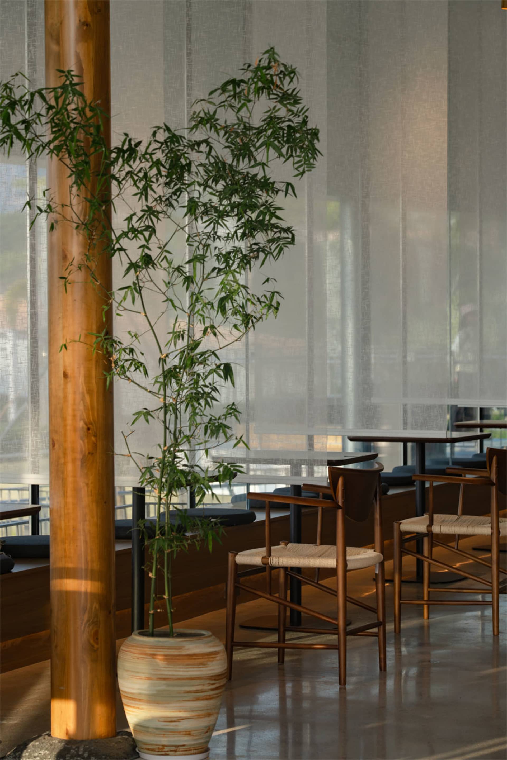 A dimly lit restaurant with wooden floors and furniture, creating a warm and inviting atmosphere with tables and chairs