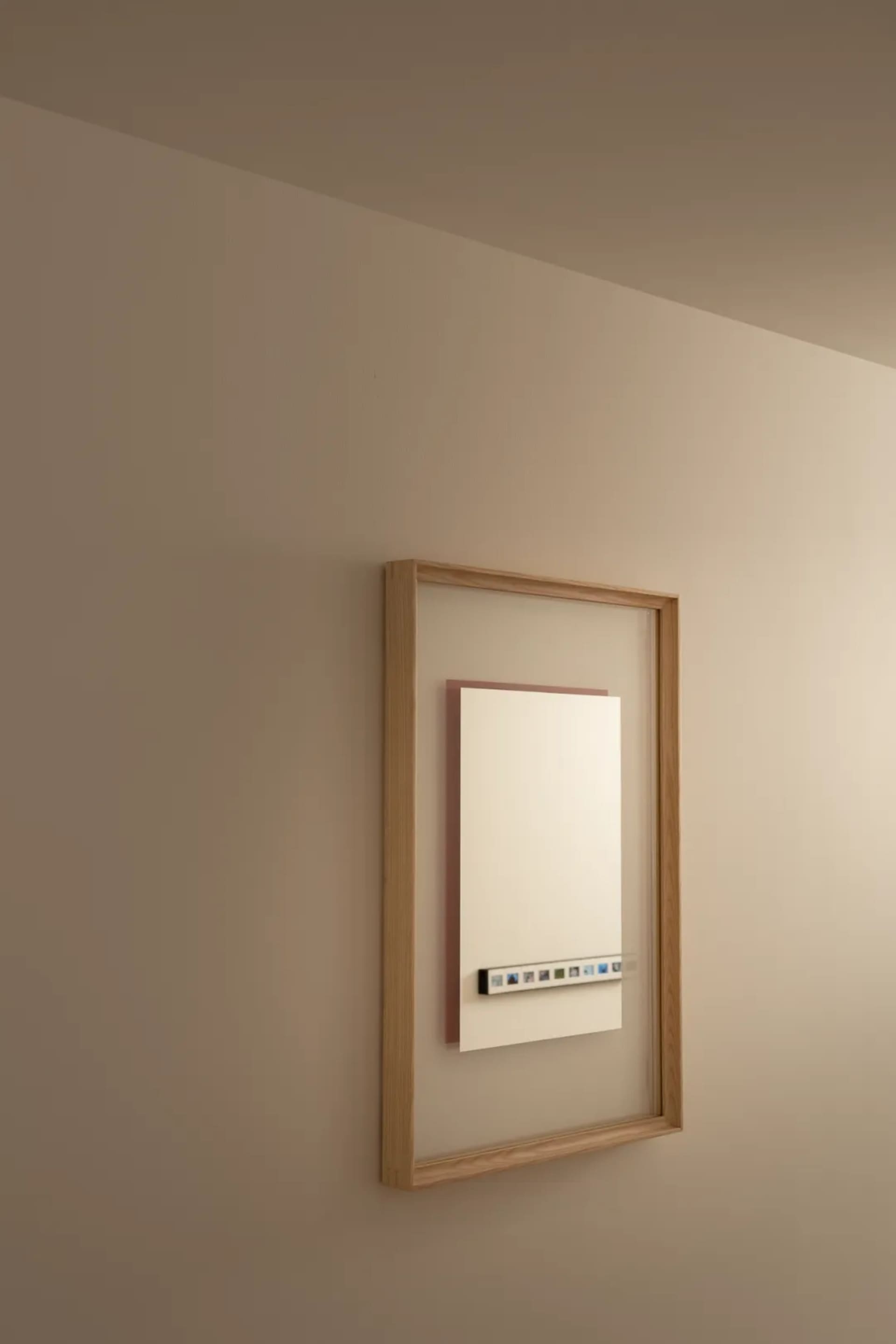 A modern residential bathroom with a white heater and mirror on the wall, mounted on a wooden frame, in a well-lit space with a clean and organized atmosphere