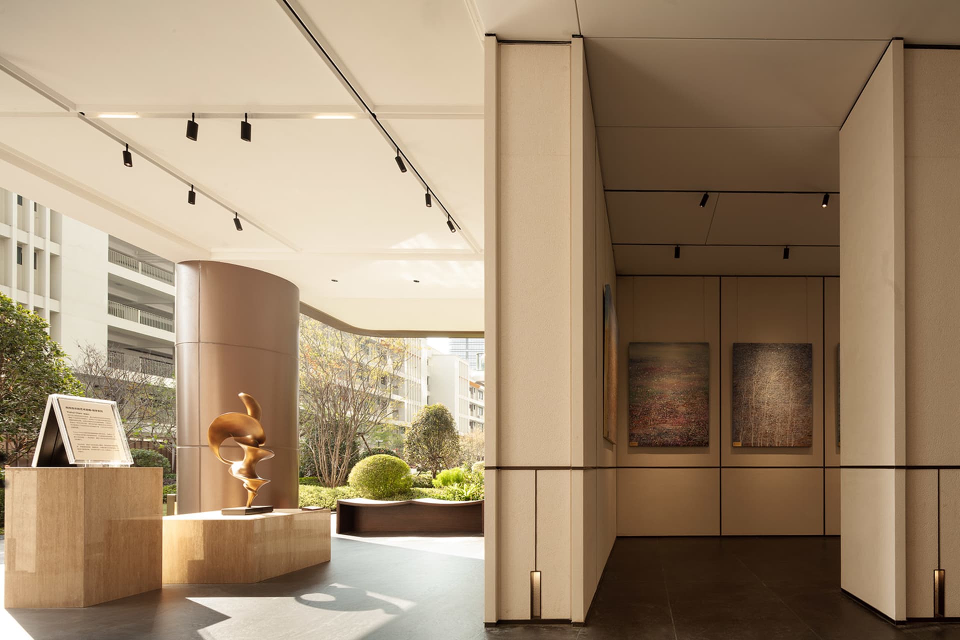 A well-lit modern room with wood, stone, and glass features, adorned with paintings and providing a comfortable space for art appreciation
