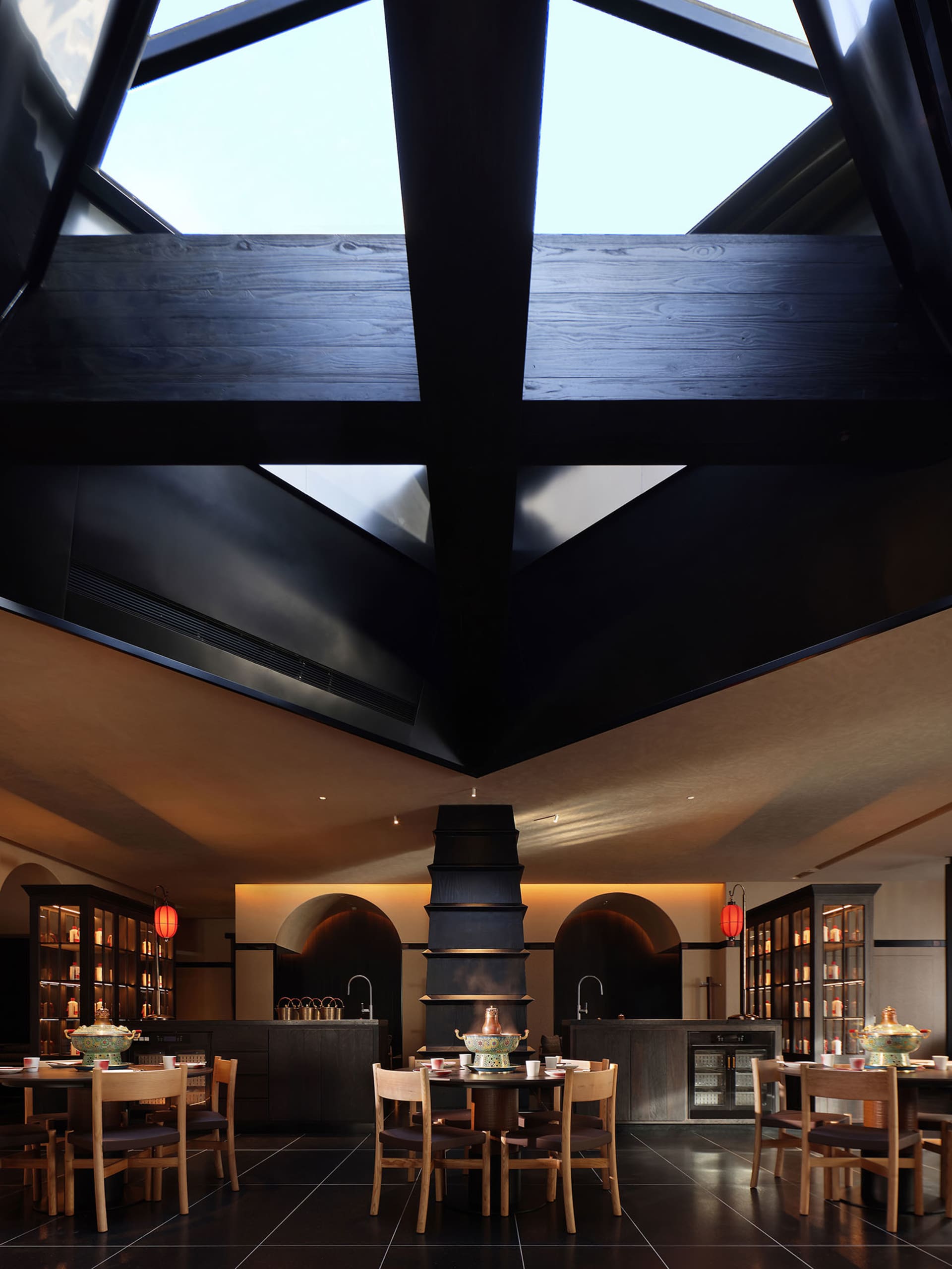 Bright and inviting restaurant with a large dining area, natural light from a skylight, and modern wood and glass materials