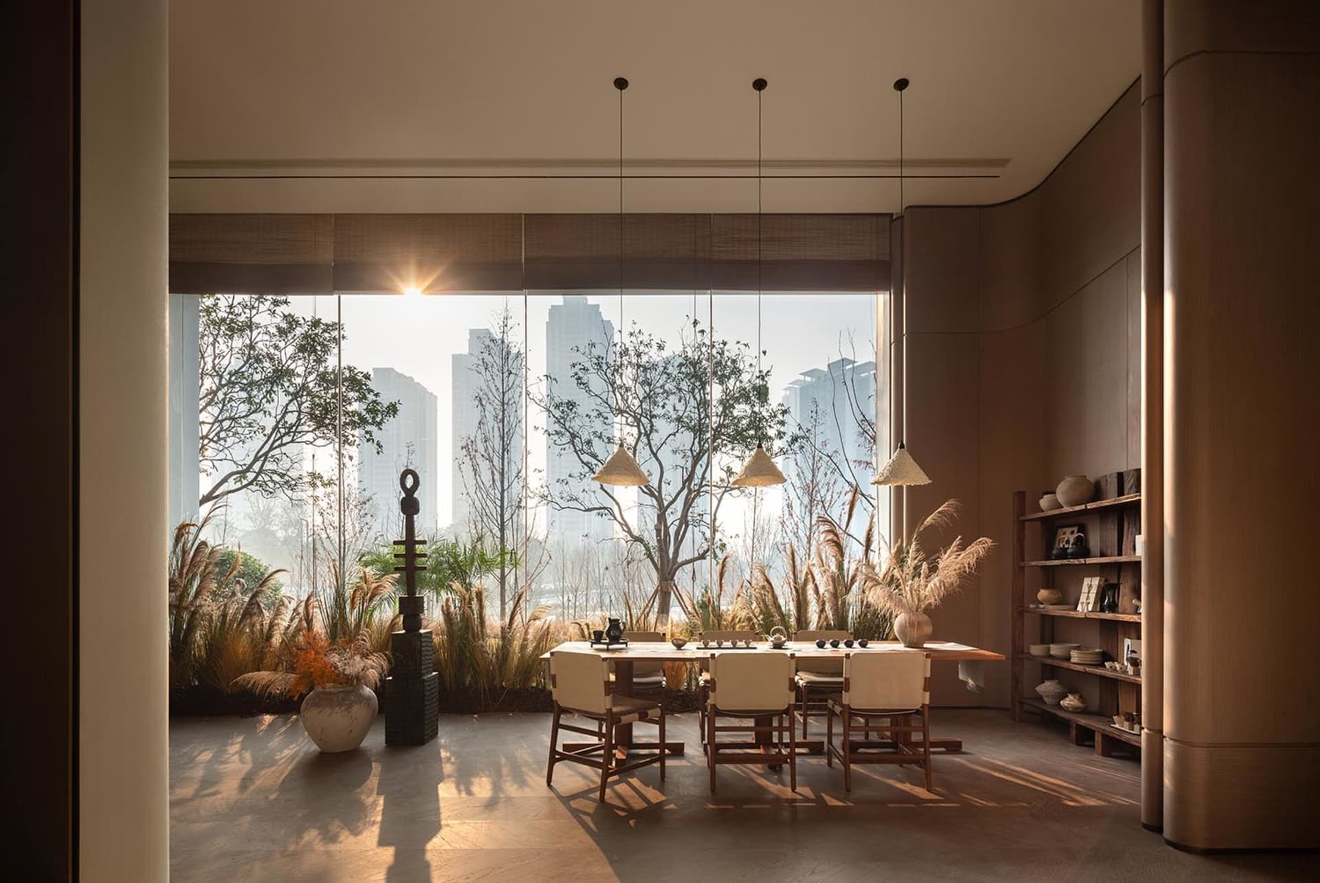 A well-lit dining room with a wooden dining table and chairs, surrounded by a modern open-concept space with a large window and natural light