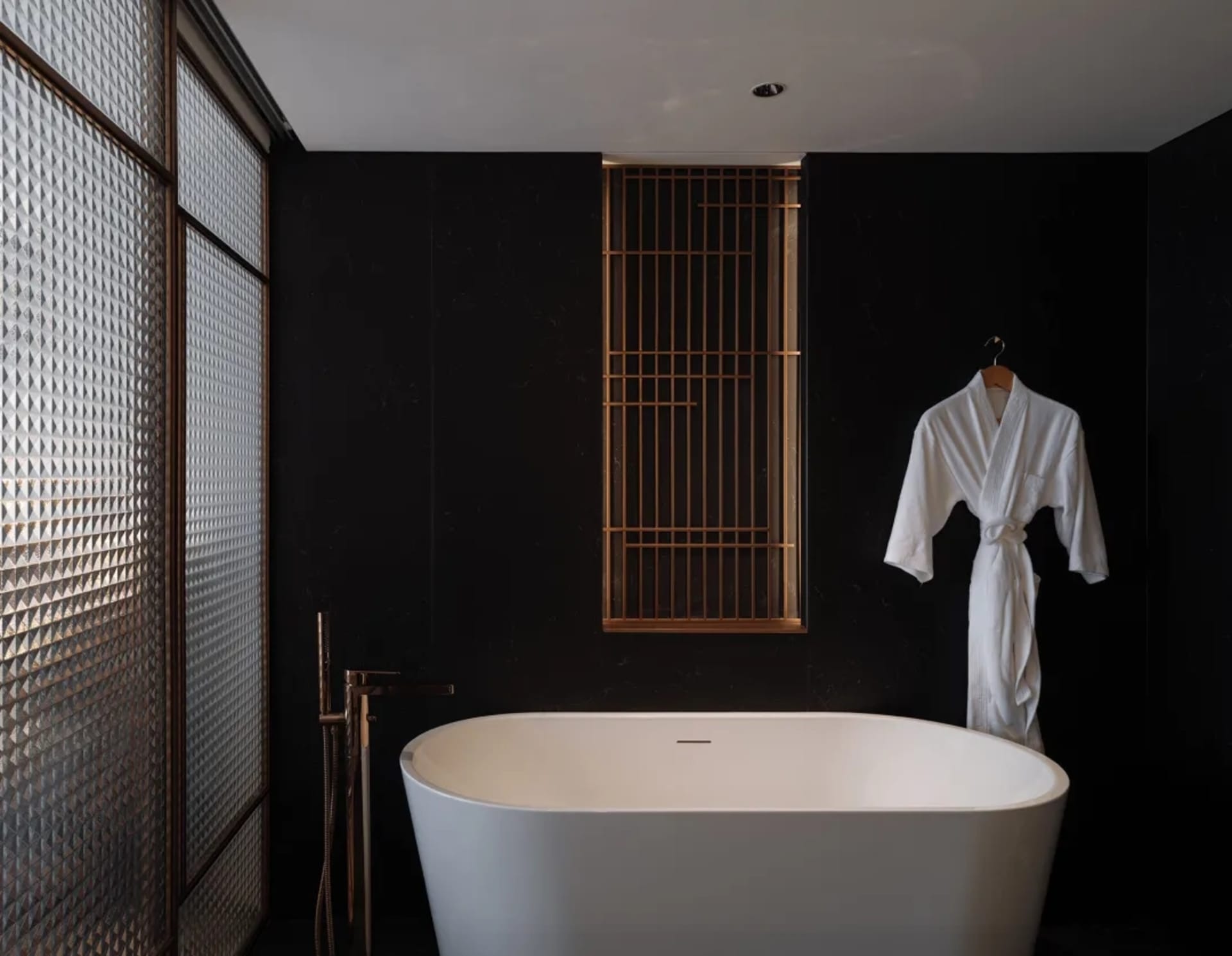 Modern bathroom with a white clawfoot tub, toilet, and sink in a dimly lit space
