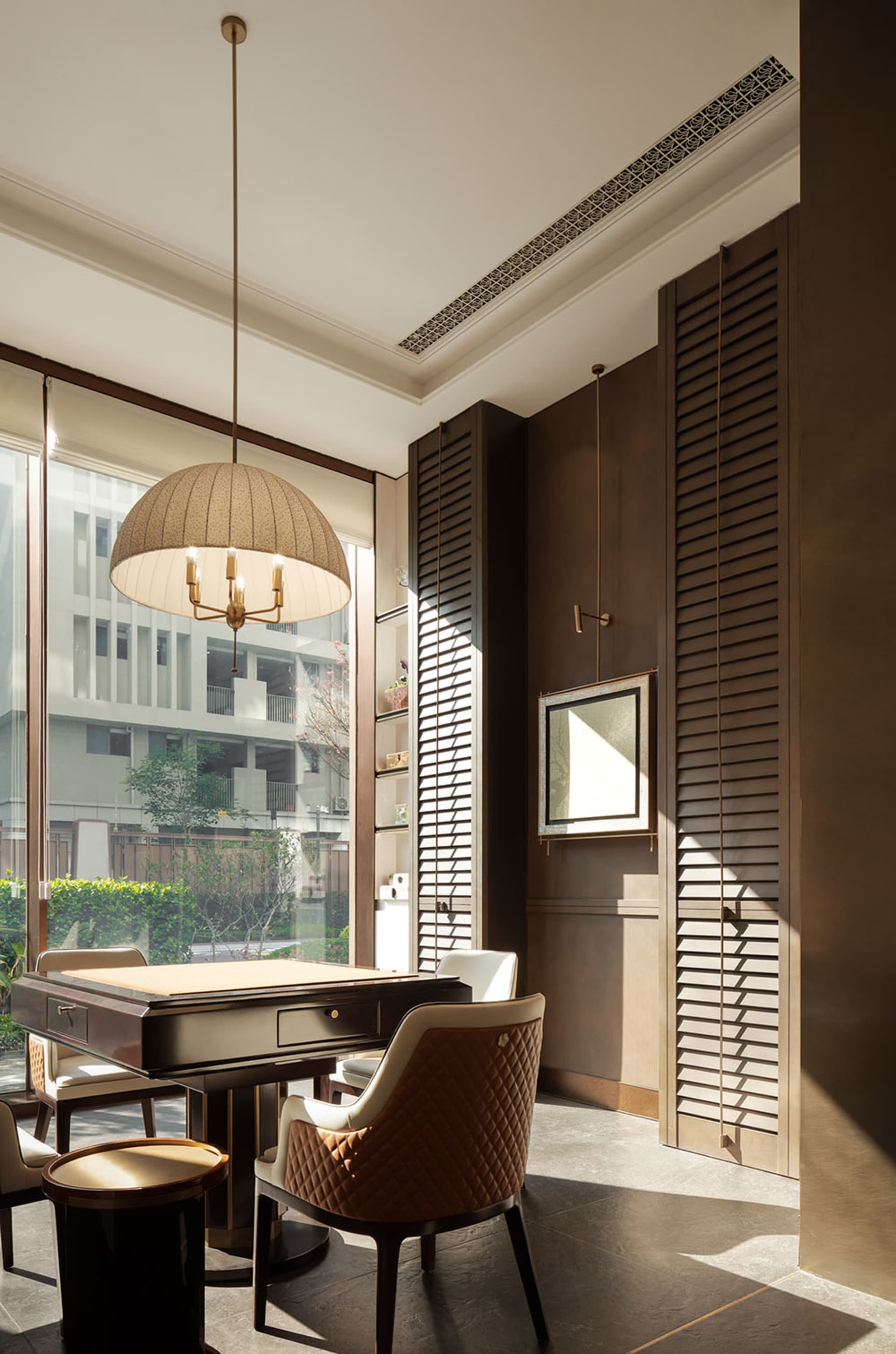 A well-lit modern dining room with a wooden table and white chairs, surrounded by a hanging lamp and comfortable furniture