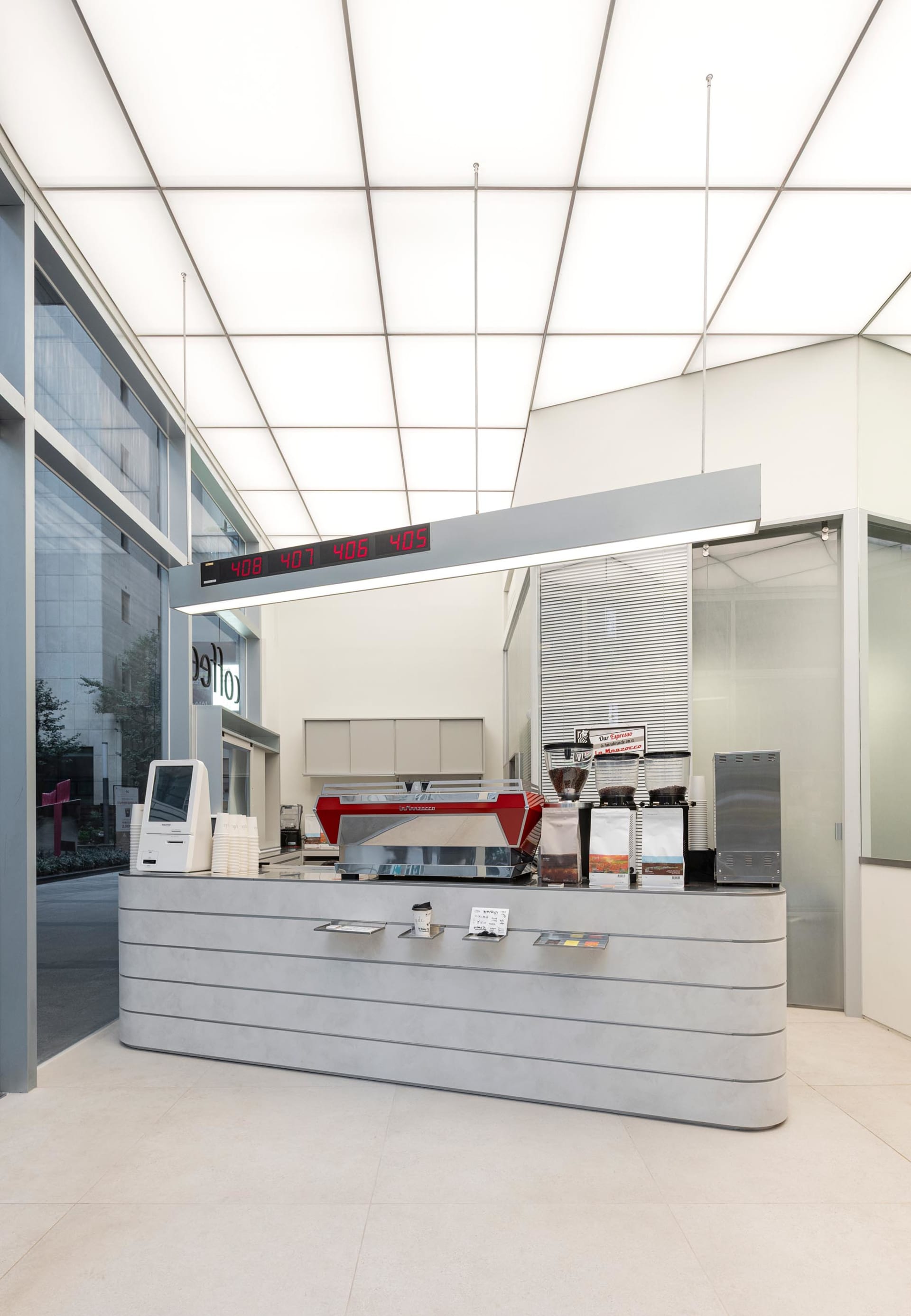 A well-lit coffee shop with a modern design, featuring a counter with coffee beans and cups, and a welcoming atmosphere