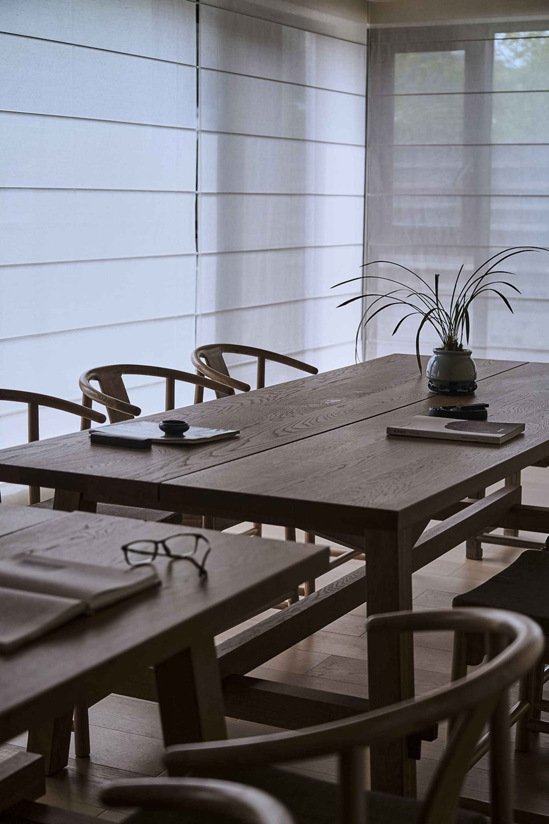 A warm and inviting dining area with a wooden table and chairs, surrounded by a potted plant and natural light