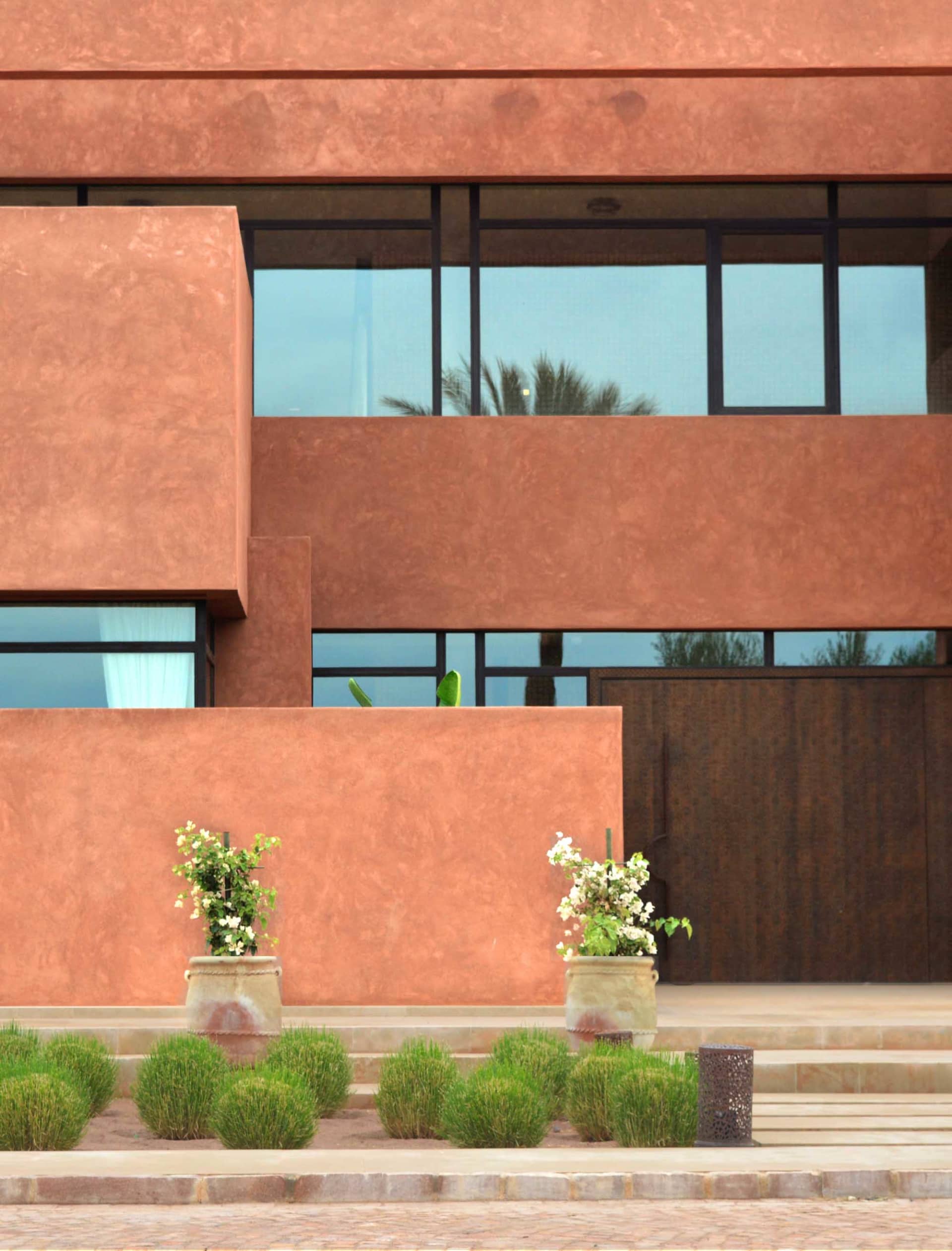 A modern red building with a large window, concrete exterior, and natural light pouring in