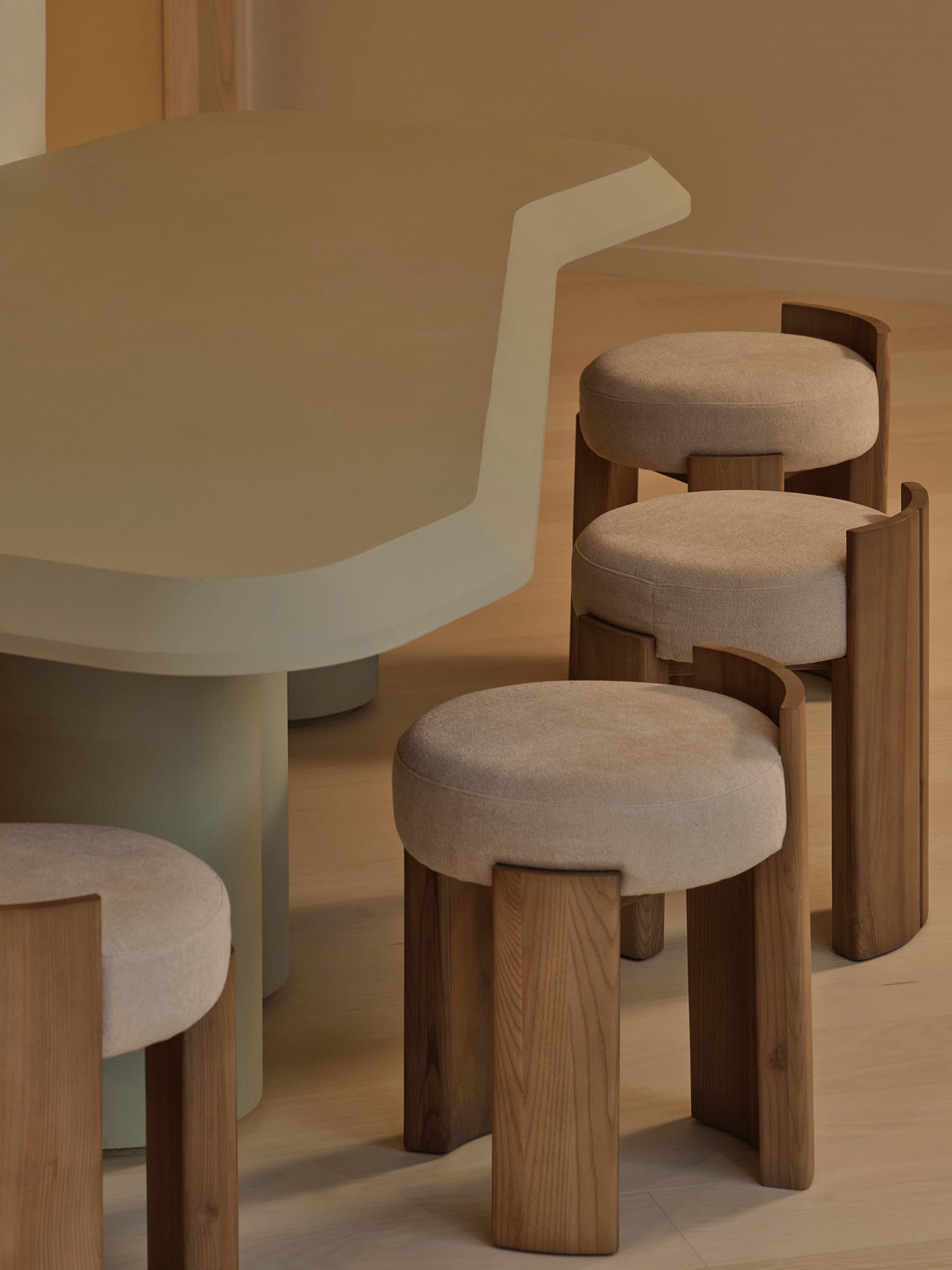 Modern kitchen with a white dining table, brown stools, and a chair, featuring a counter with a sink and warm soft lighting