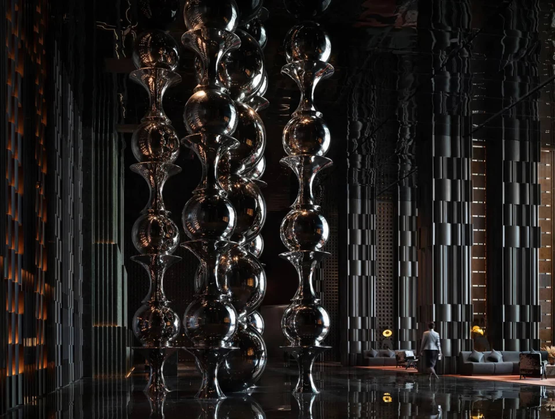 A modern living space with glass balls, chairs, a couch, and a person, featuring a contemporary and minimalist style with a focus on glass and reflective surfaces, in a dimly lit atmosphere