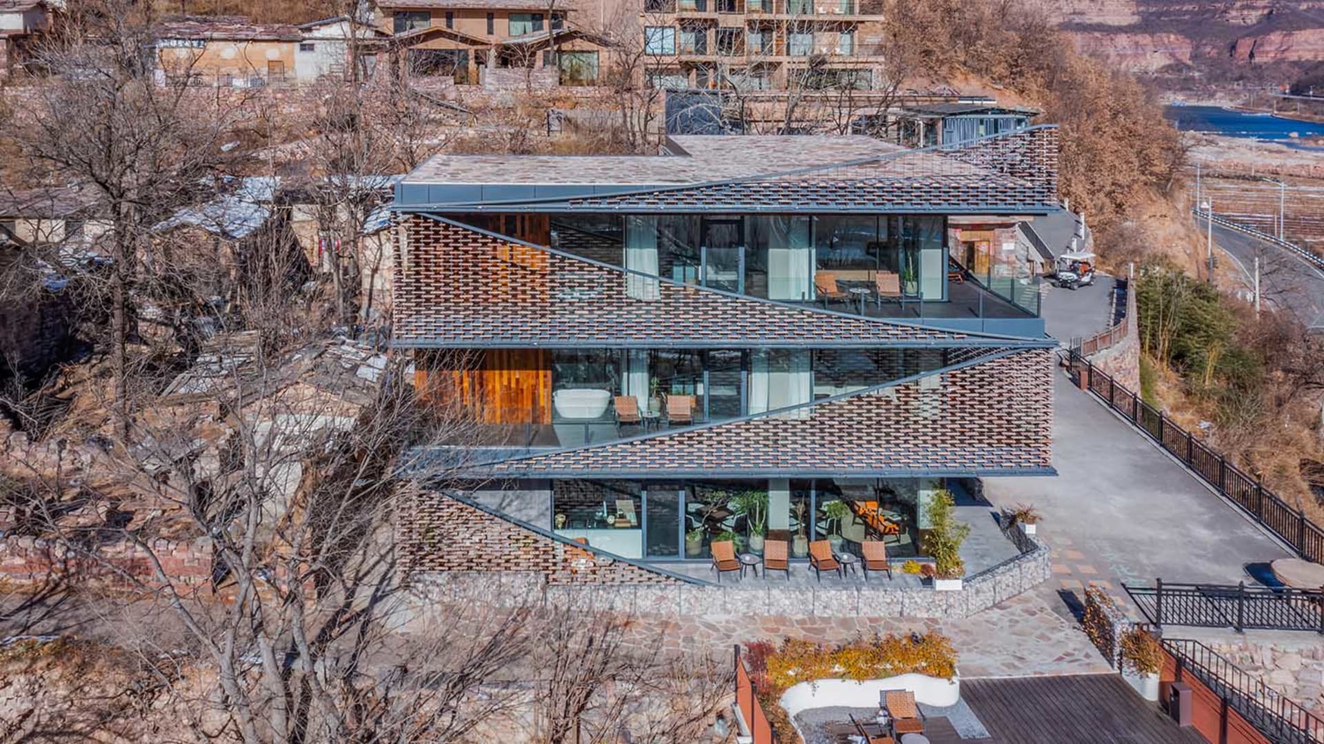 Modern multi-story building with a curved glass wall, concrete exterior, and interior furniture and decor