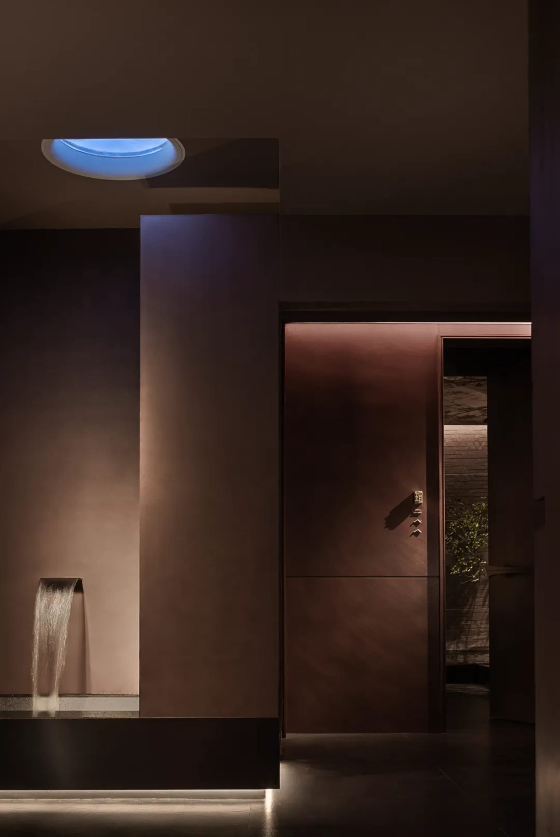 Bathroom with a brown color scheme, stone walls, and a tile floor, featuring a shower on the left and a toilet on the right in a dimly lit space